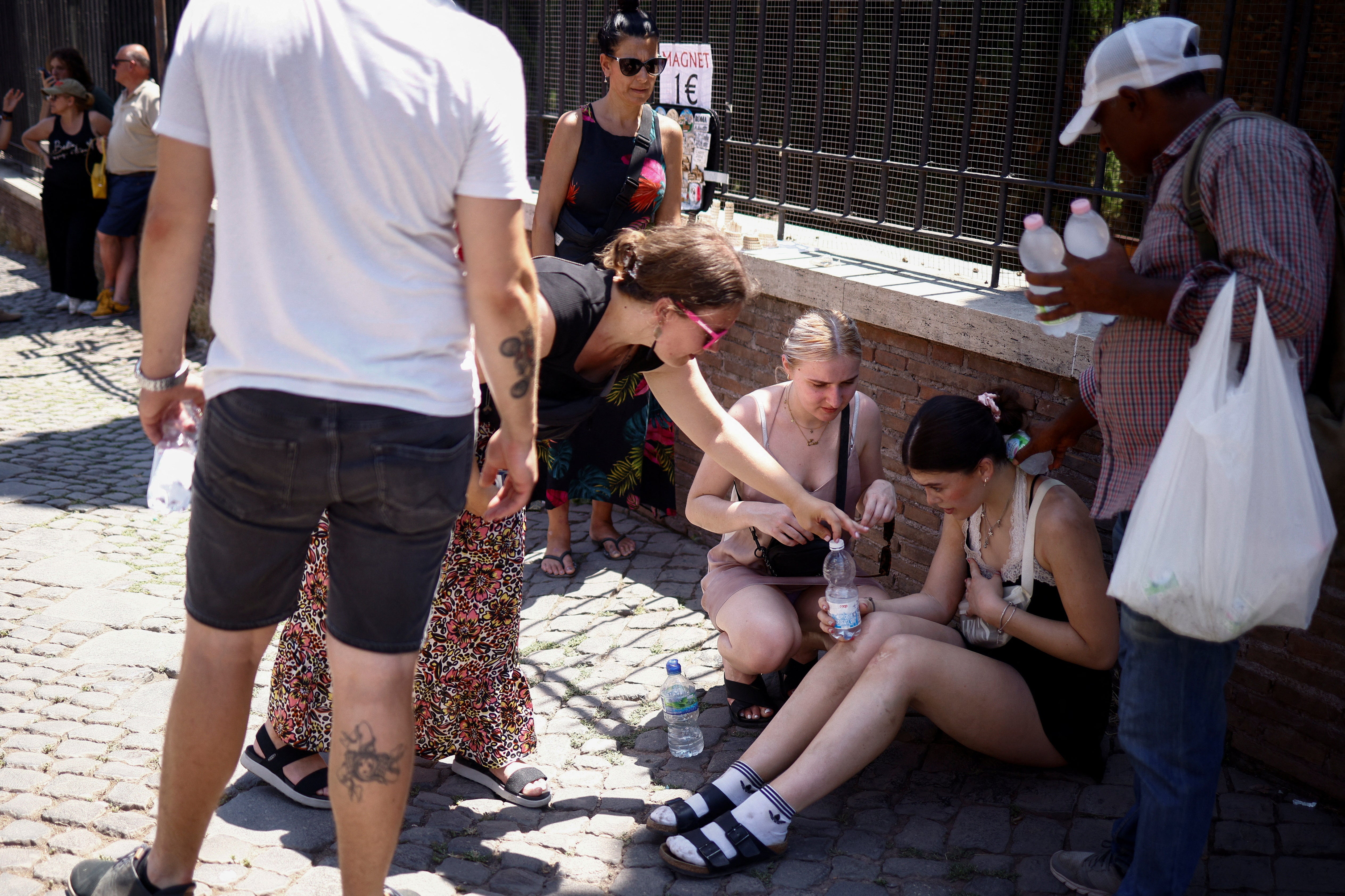 A tourist from the UK receives help near the Colosseum after fainting during a heatwave across Italy