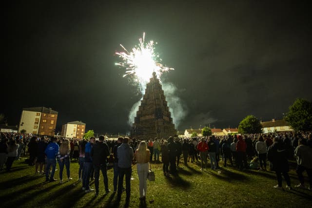 People watch the burning of the loyalist Corcrain bonfire in Portadown, Co Armagh on Monday night (PA)