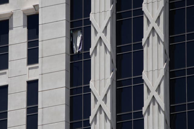 <p>A curtain hangs out of a broken window on a hotel tower at Caesars Palace Hotel & Casino</p>