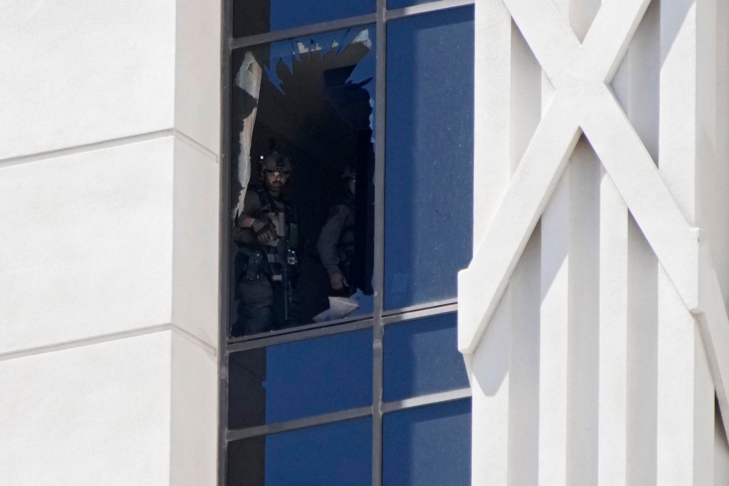 A police officer looks out of a broken window on a hotel tower at Caesars Palace hotel-casino, Tuesday, July 11, 2023