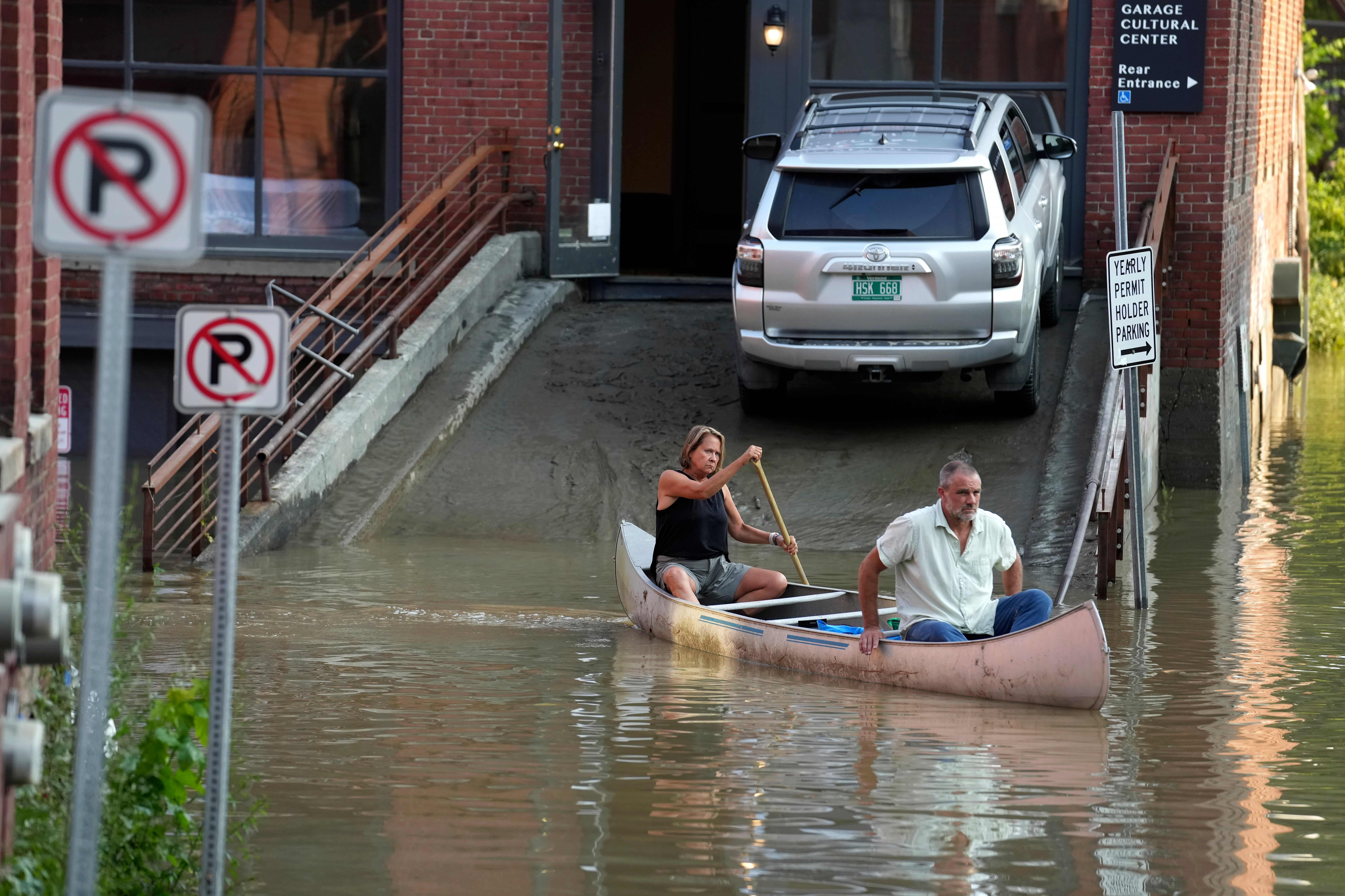 Jodi Kelly, left, practice manager at Stonecliff Veterinary Surgical Center, behind, and her husband, veterinarian Dan Kelly, use a canoe to remove surgical supplies from the flood-damaged centre