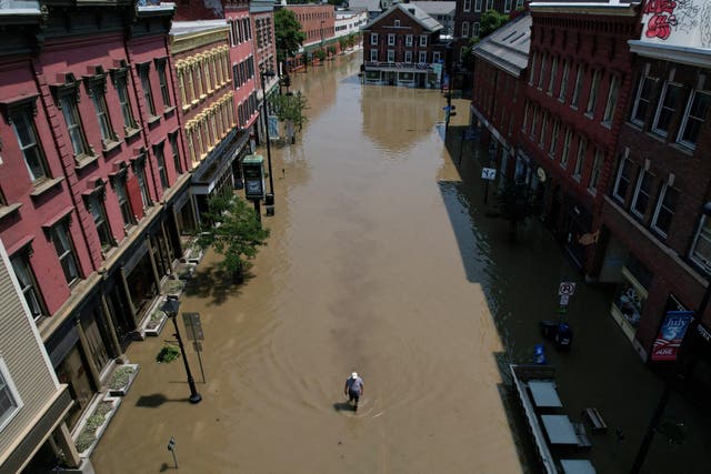 <p>A man walks down street flooded by recent rain storms in Montpelier, Vermont</p>