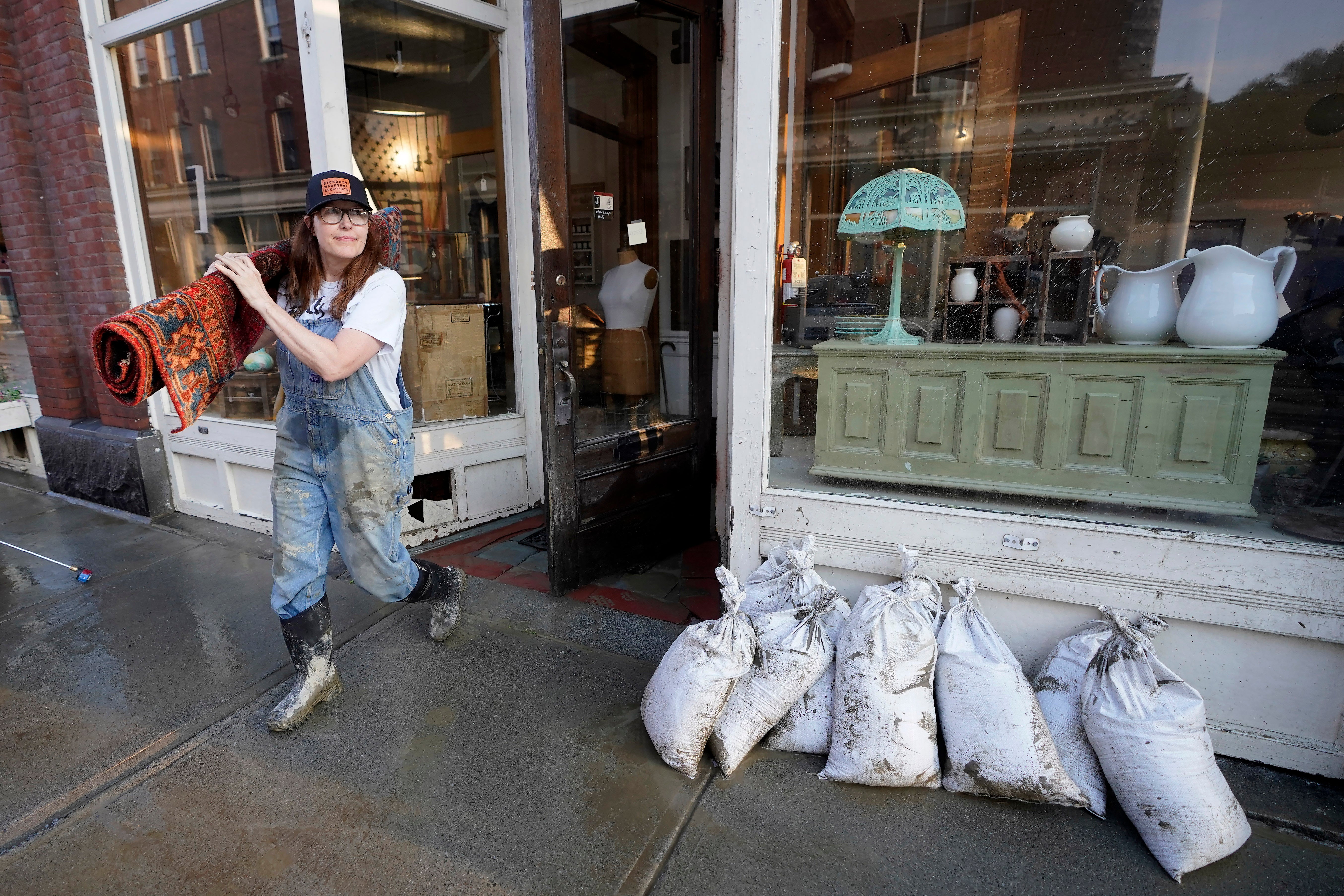 Juliana Jennings removes a wet Persian rug from the flood-damaged antique, art, and furnishing store she shares with her husband, in downtown Montpelier, Vermont