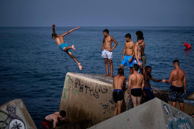 A youth jumps into the sea on a breakwater in Barcelona (AP Photo/Emilio Morenatti)