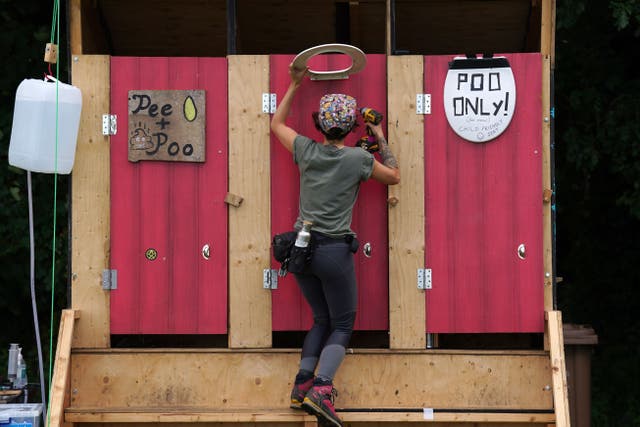A volunteer puts signage on the toilets at the climate camp in Bo’ness (Andrew Milligan/PA)