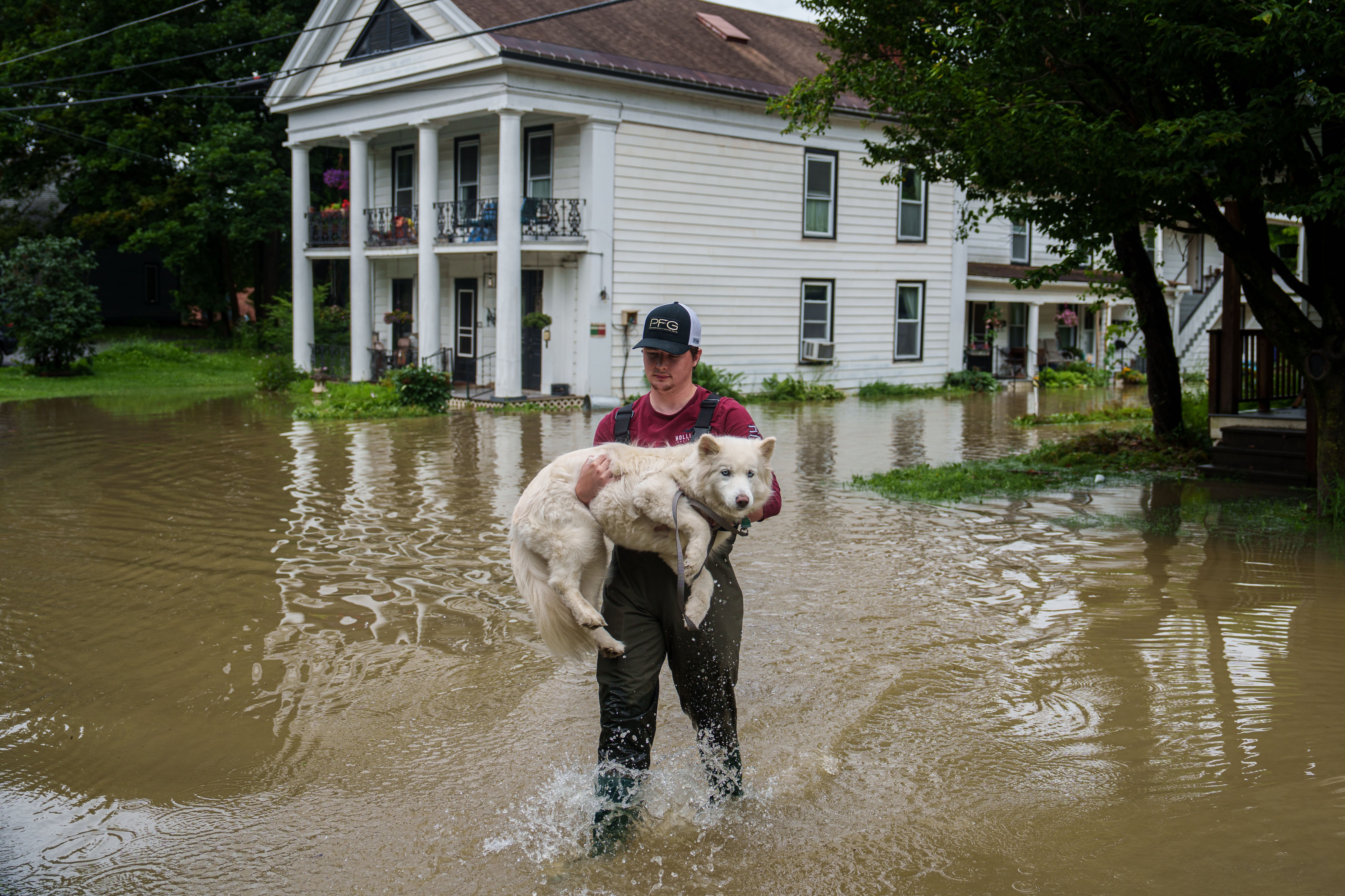 A dog’s best friend: during massive flooding in Vermont, Tyler Jovic carries his neighbour’s pet to dry ground