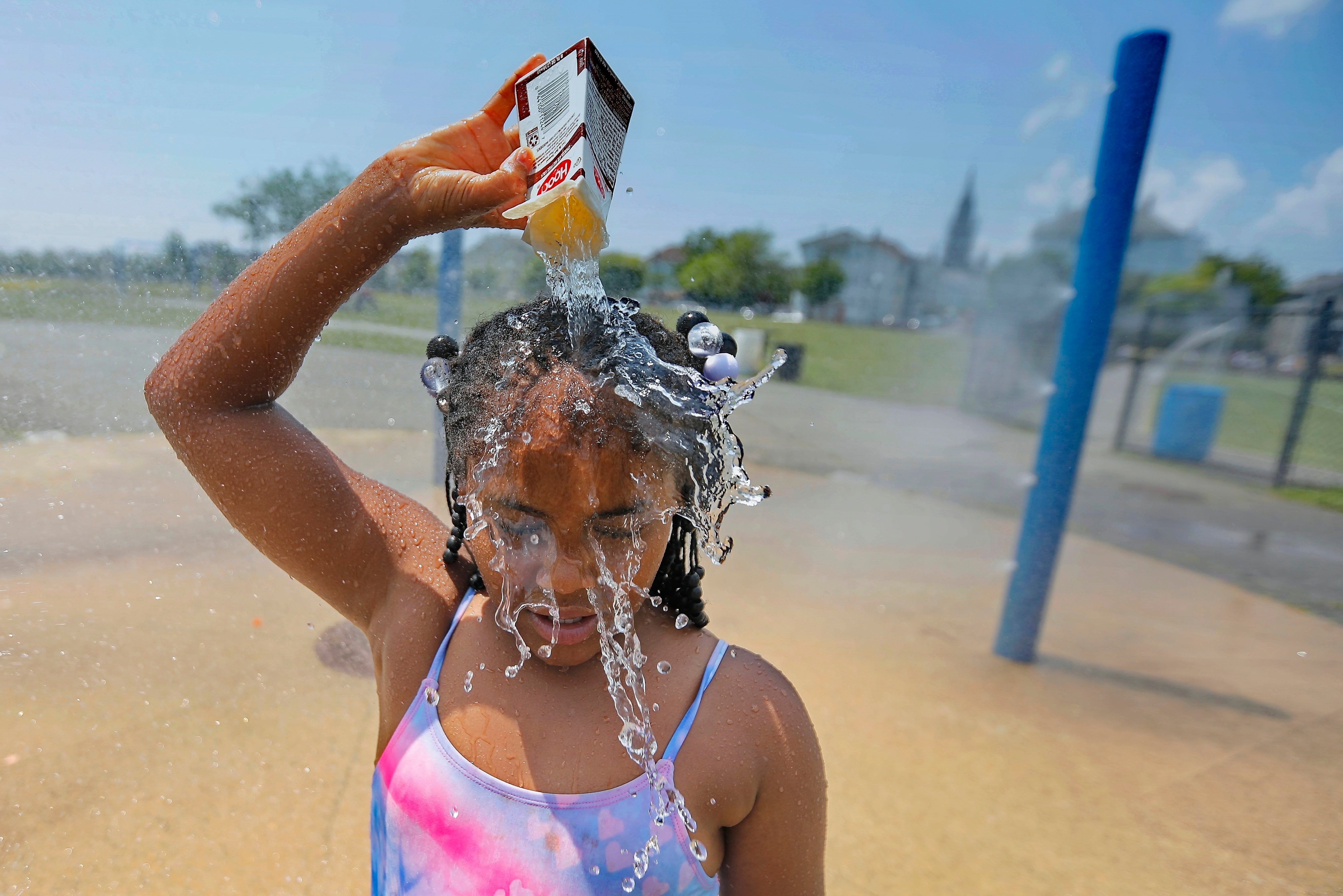 Ja-Veah Cheney, 9, pours water over her head, taking shelter from the sweltering heat at the splash pad station at Riverside Park in New Bedford, Mass., on July 12, 2023