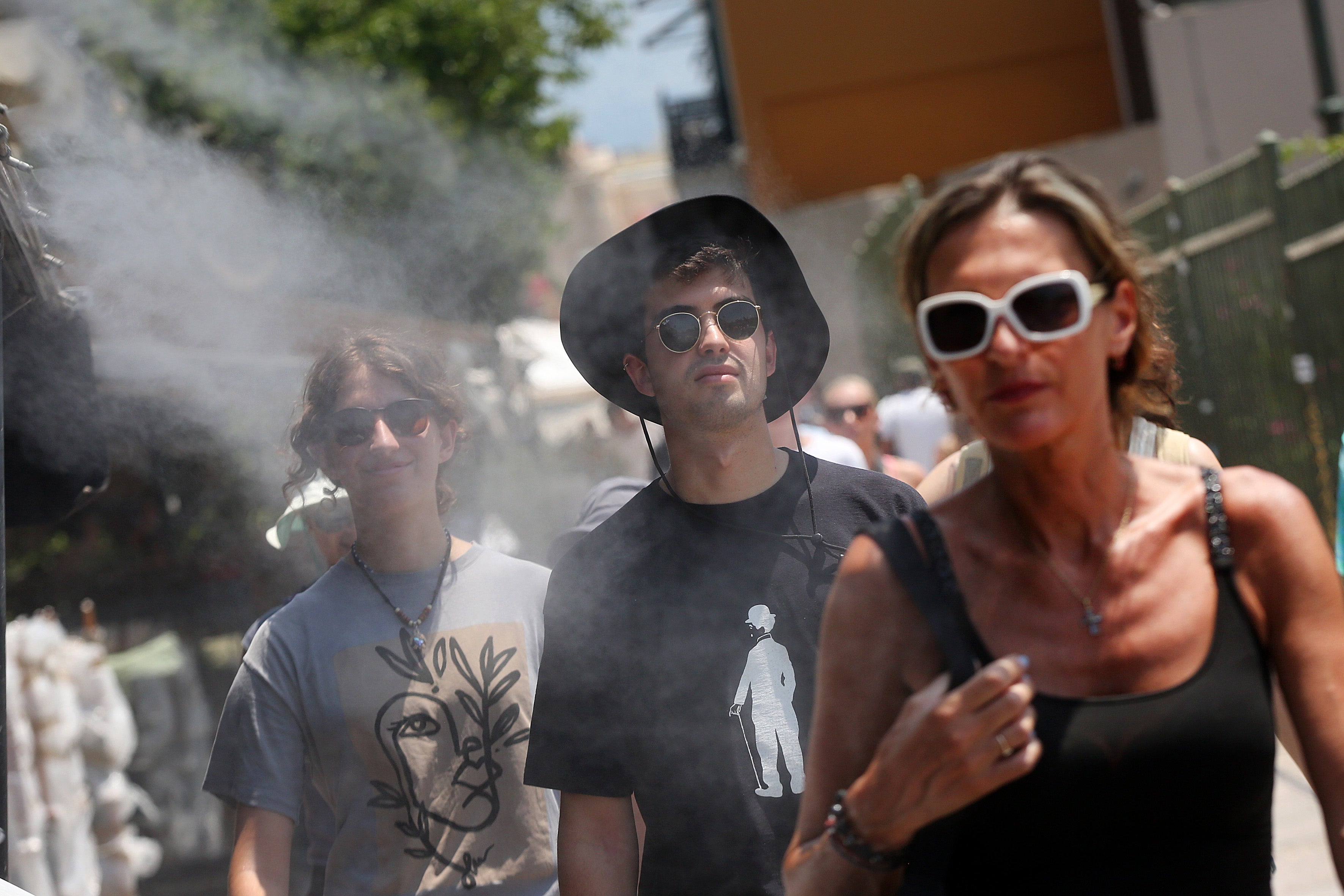 <p>People cool off from a water spray device amid high temperatures in Athen</p>