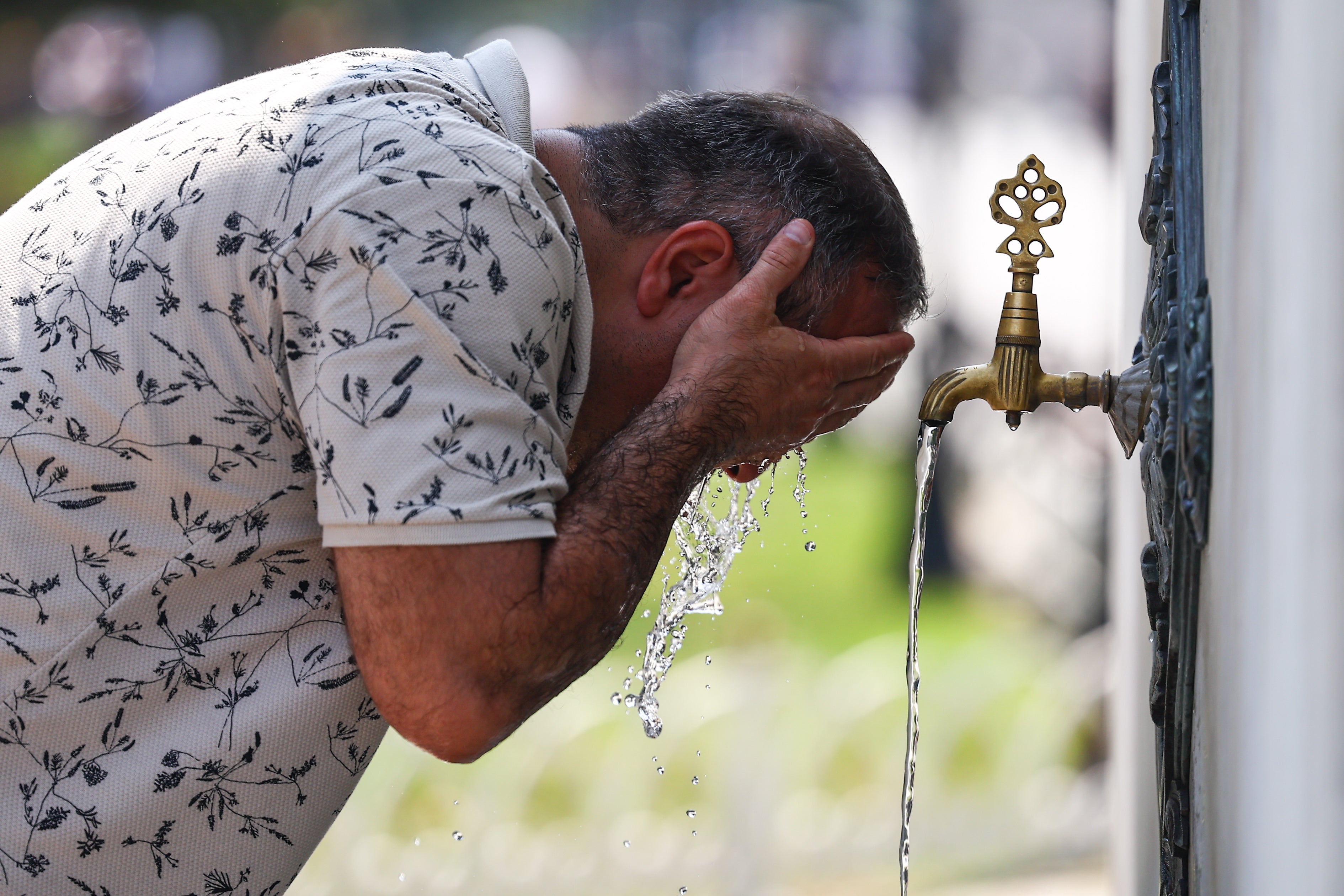 <p>A man cools off at a fountain in Istanbul, Turkey</p>