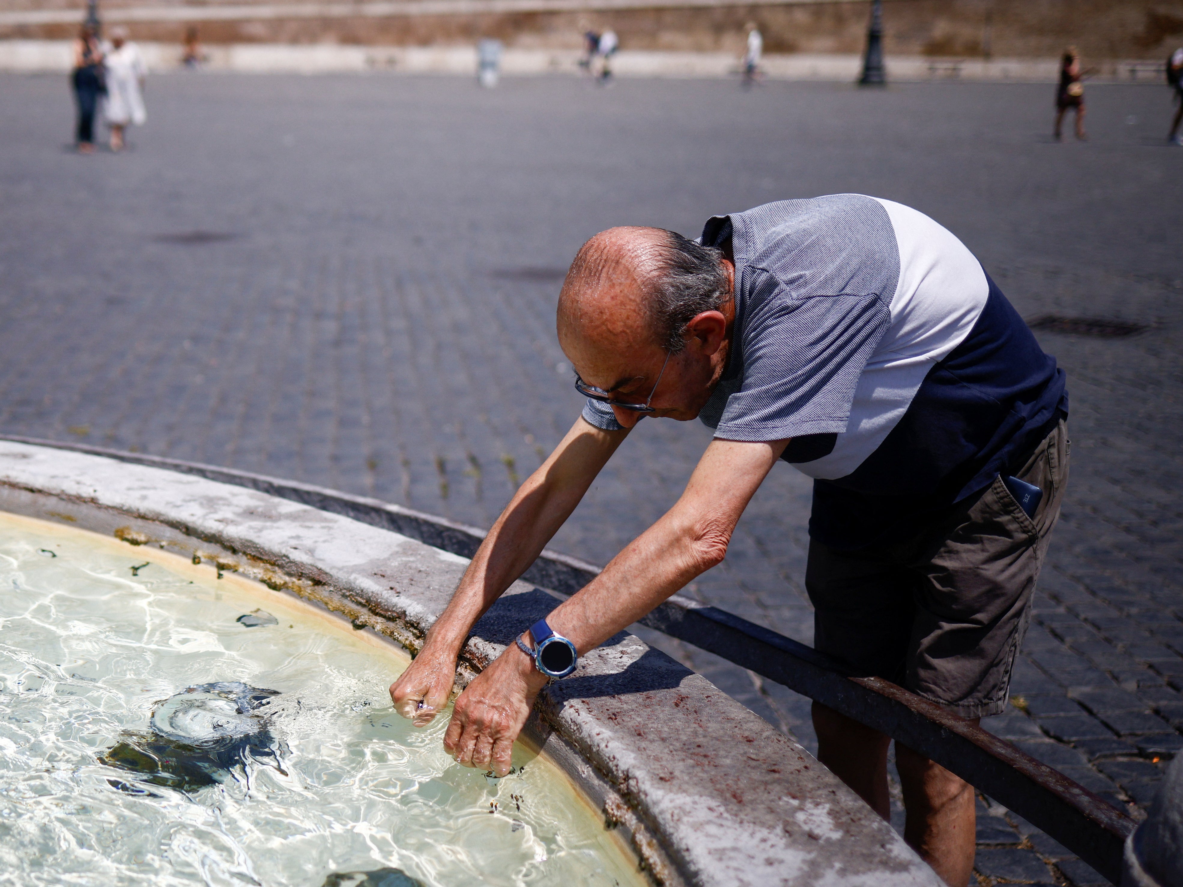 A man cools off at a fountain in Rome