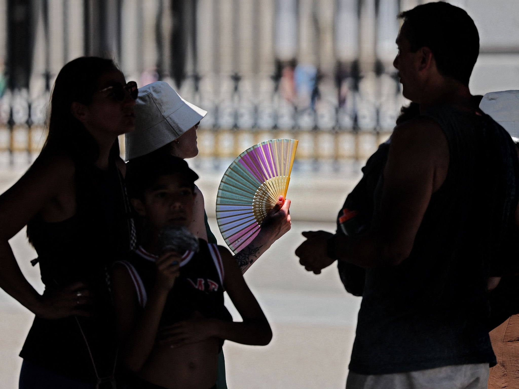 Tourists stand in the shade on a visit to the Royal Palace in Madrid