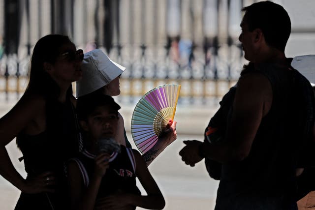 <p>Tourists stand in the shade on a visit to the Royal Palace in Madrid</p>