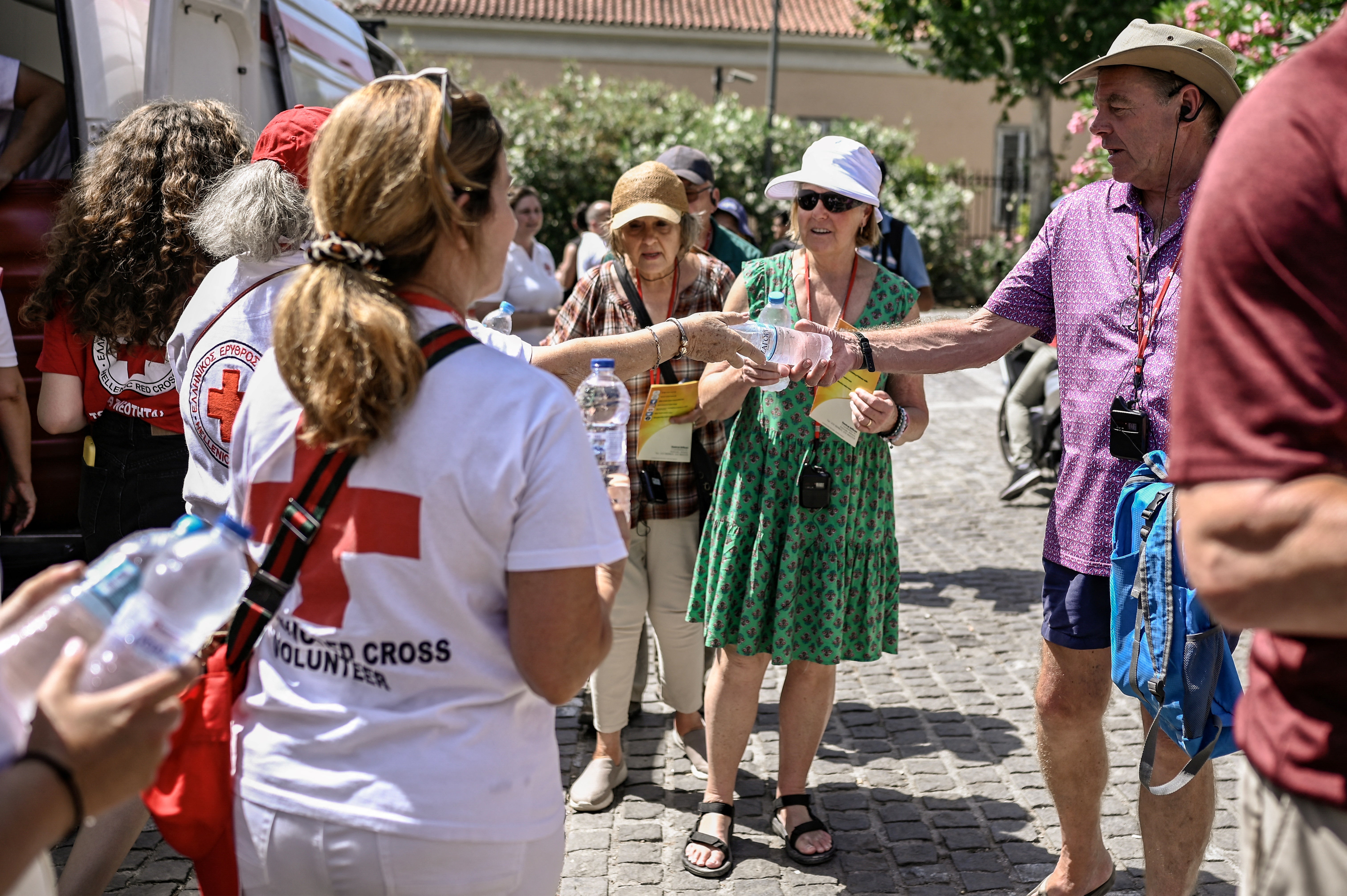Red Cross volunteers hand out bottles of water in Athens