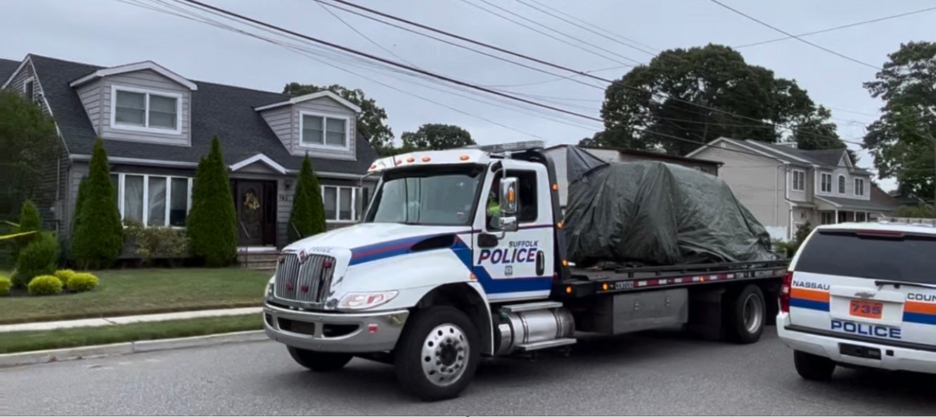 Police hauled a large tarp-covered piece of evidence after the suspect’s arrest