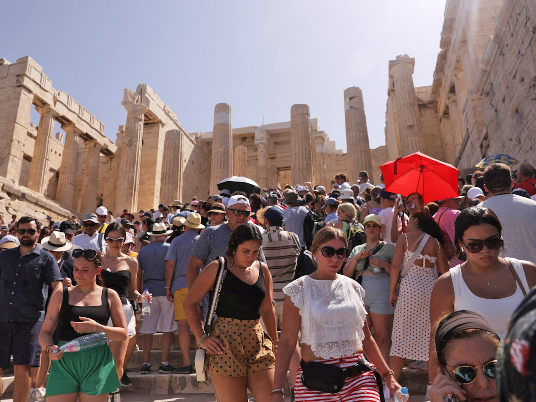 Visitors walk in front of the Acropolis, in Athens, as the Cerberus heatwave hit Greece on Saturday