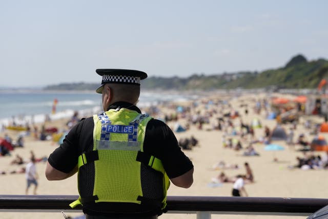 A police officer looks out over Bournemouth beach, after Joe Abbess, 17, and Sunnah Khan, 12, drowned and eight other people were treated by paramedics after they were suspected to have been caught in a riptide next to the pier at the Dorset seaside resort (Andrew Matthews/PA)