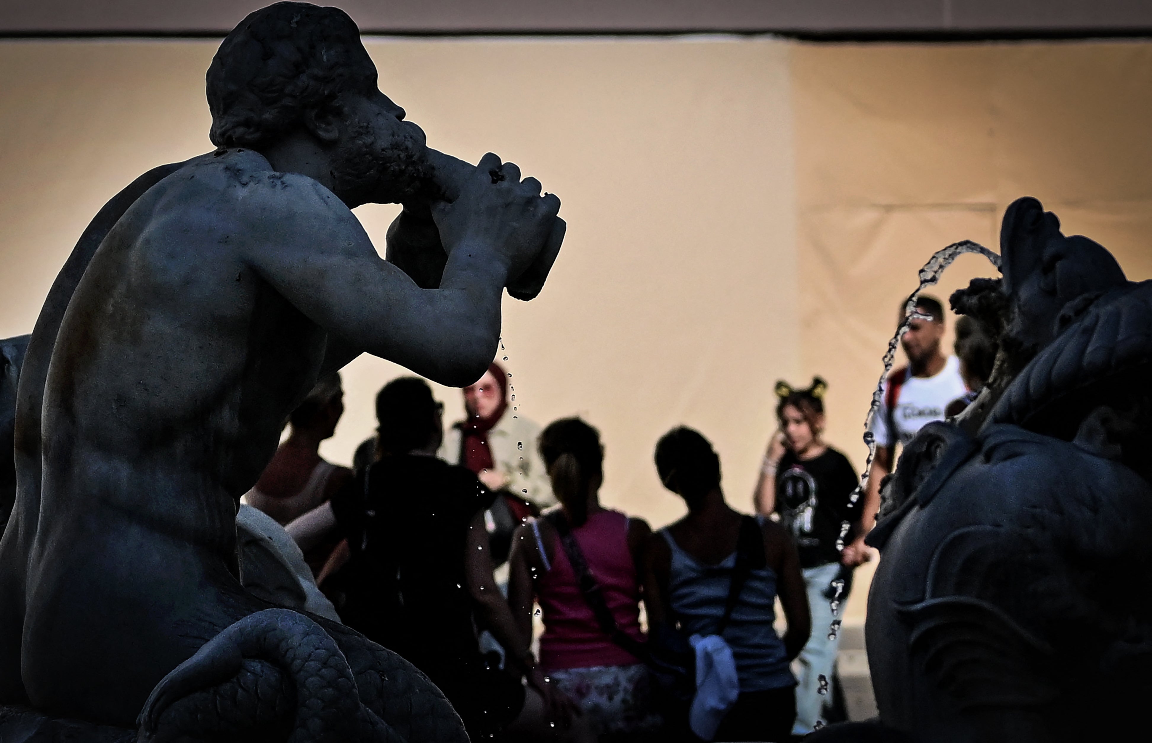 <p>People stand next to a fountain at Piazza Navona in central Rome, on July 14, 2023, as Italy is hit by a heatwave</p>