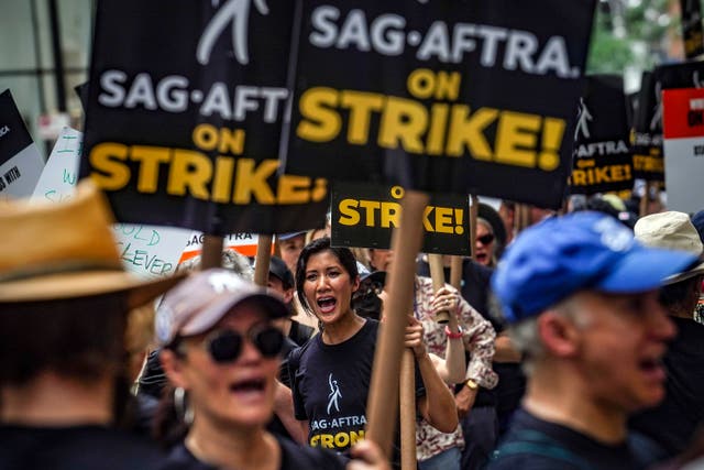 Striking writers and actors chant as they walk a picket line at NBC Universal Studios in New York (Bebeto Matthews/AP)