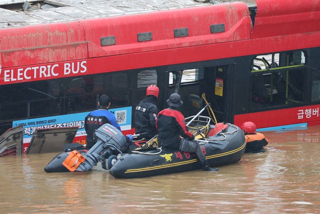 <p>South Korean rescue workers search for missing persons near a bus along a deluged road leading to an underground tunnel </p>