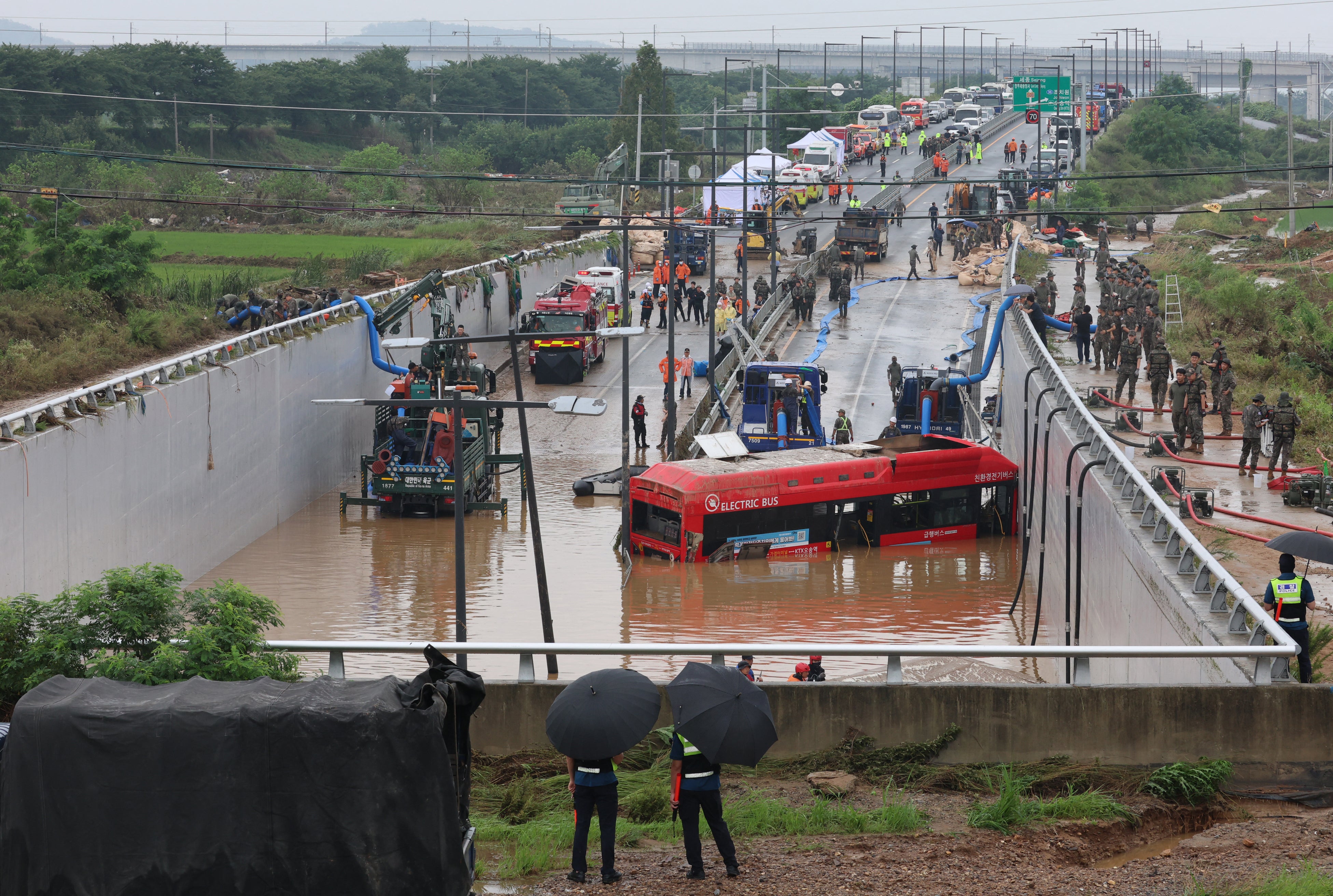 South Korean rescue workers search for missing persons along a deluged road leading to a tunnel in Cheongju