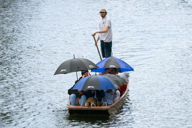 People sheltering from the rain in Cambridge during the weekend (Joe Giddens/PA)