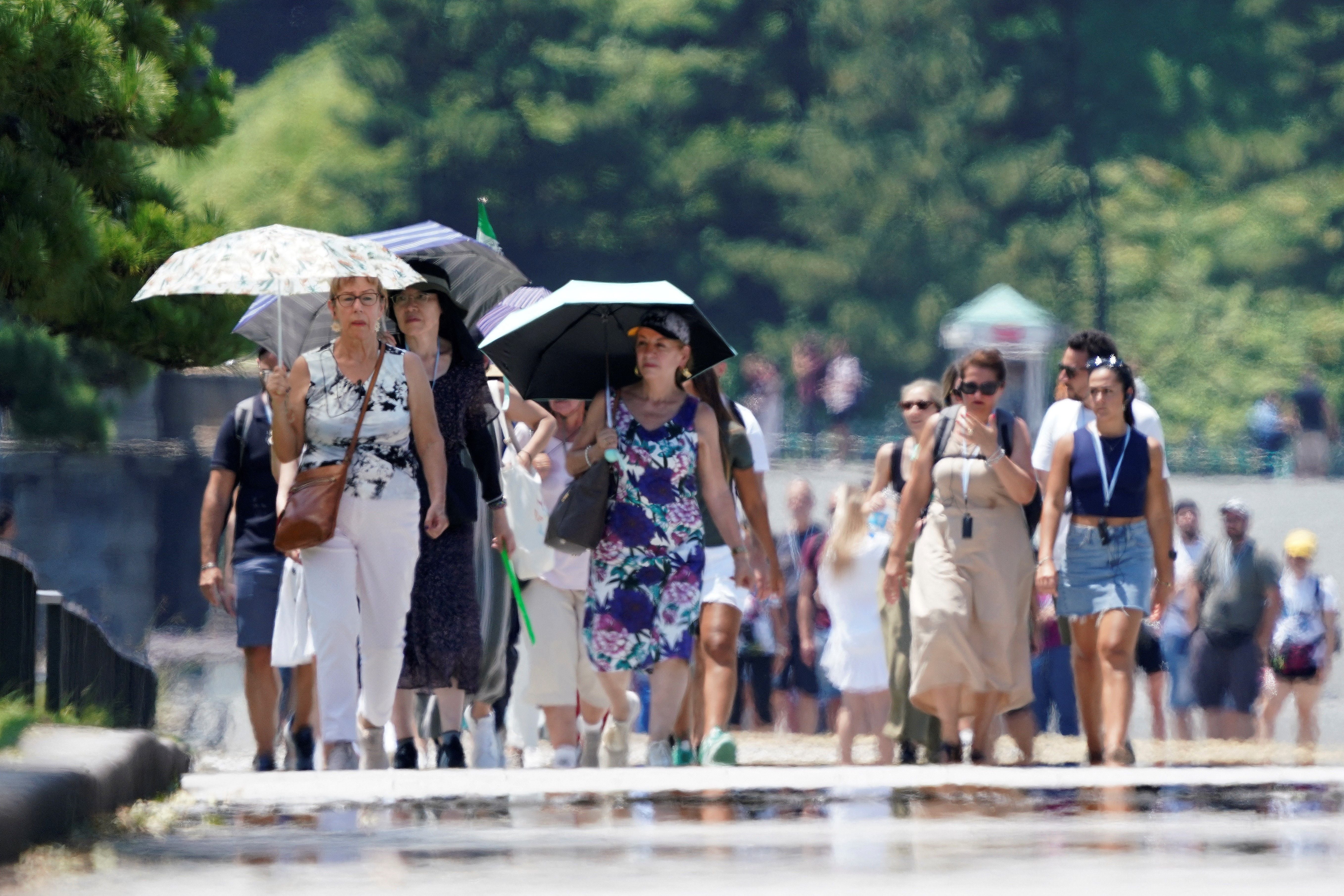 <p>Foreign tourists walk on the pavement along the Imperial Palace Gardens in the intense heat in Tokyo </p>