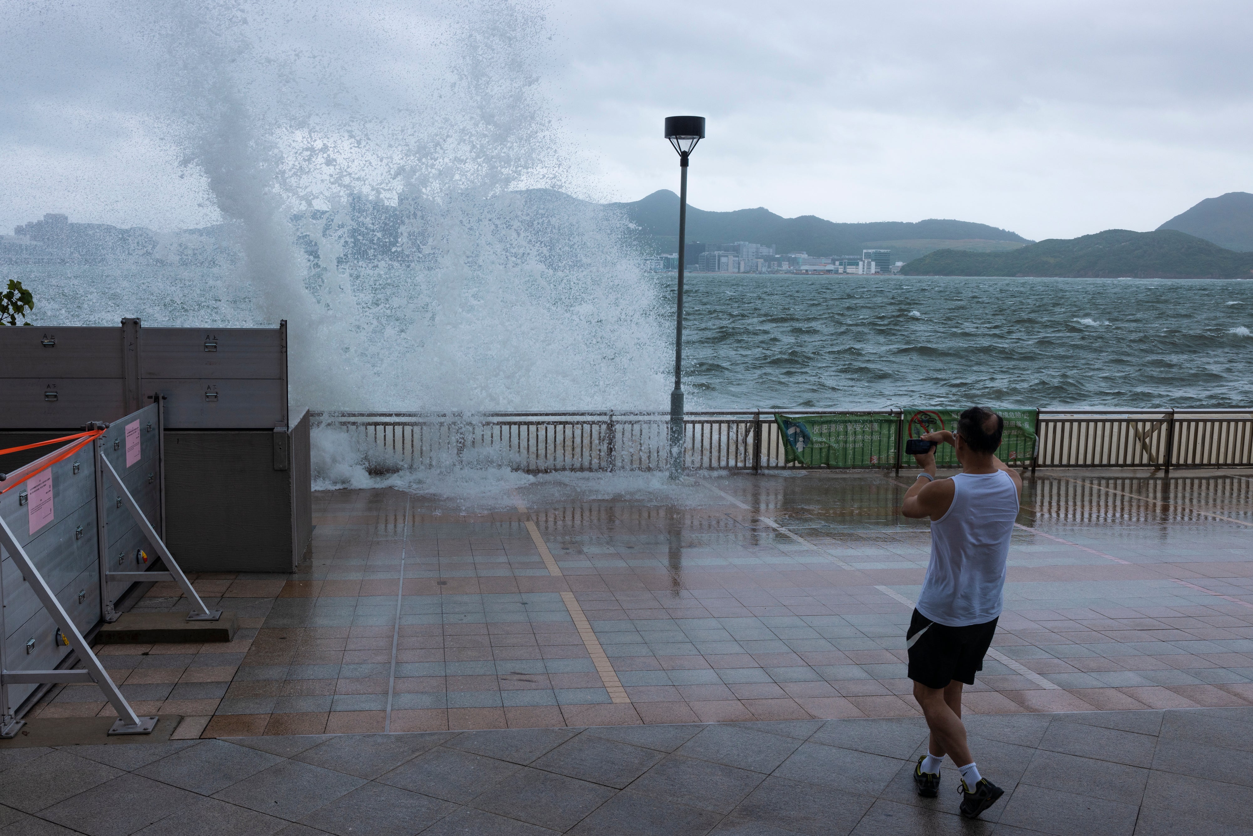 A man looks at the waves on a promenade during a typhoon in Hong Kong