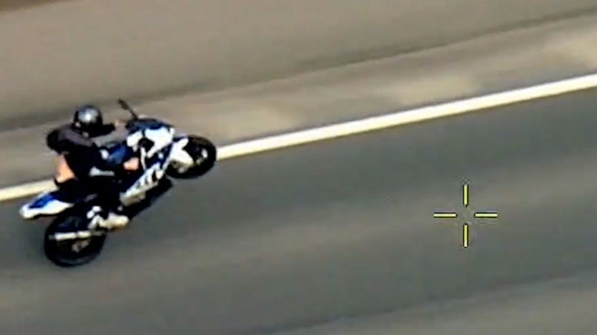 Speeding motorcyclist pulls wheelies before colliding with police car