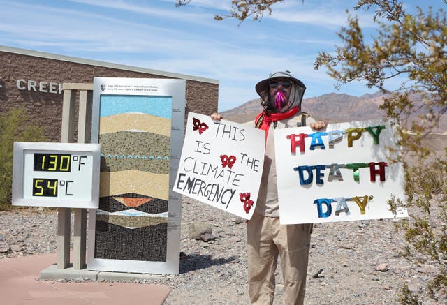 <p>A protestor stands next to a digital display of an unofficial heat reading at Furnace Creek Visitor Center during a heat wave in Death Valley National Park in Death Valley, California, on July 16, 2023</p>