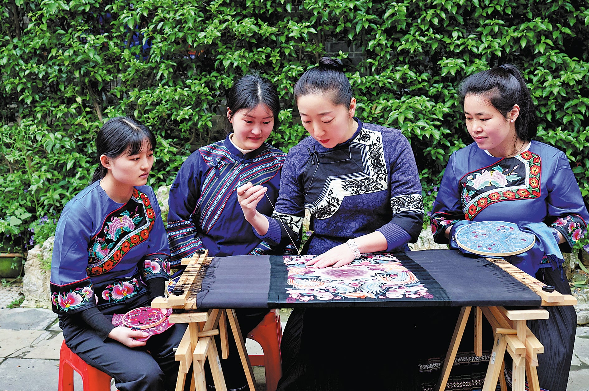 Yi Hua (second from right) demonstrates and explains Miao embroidery to local young women in Xiangxi Tujia and Miao autonomous prefecture, Hunan province