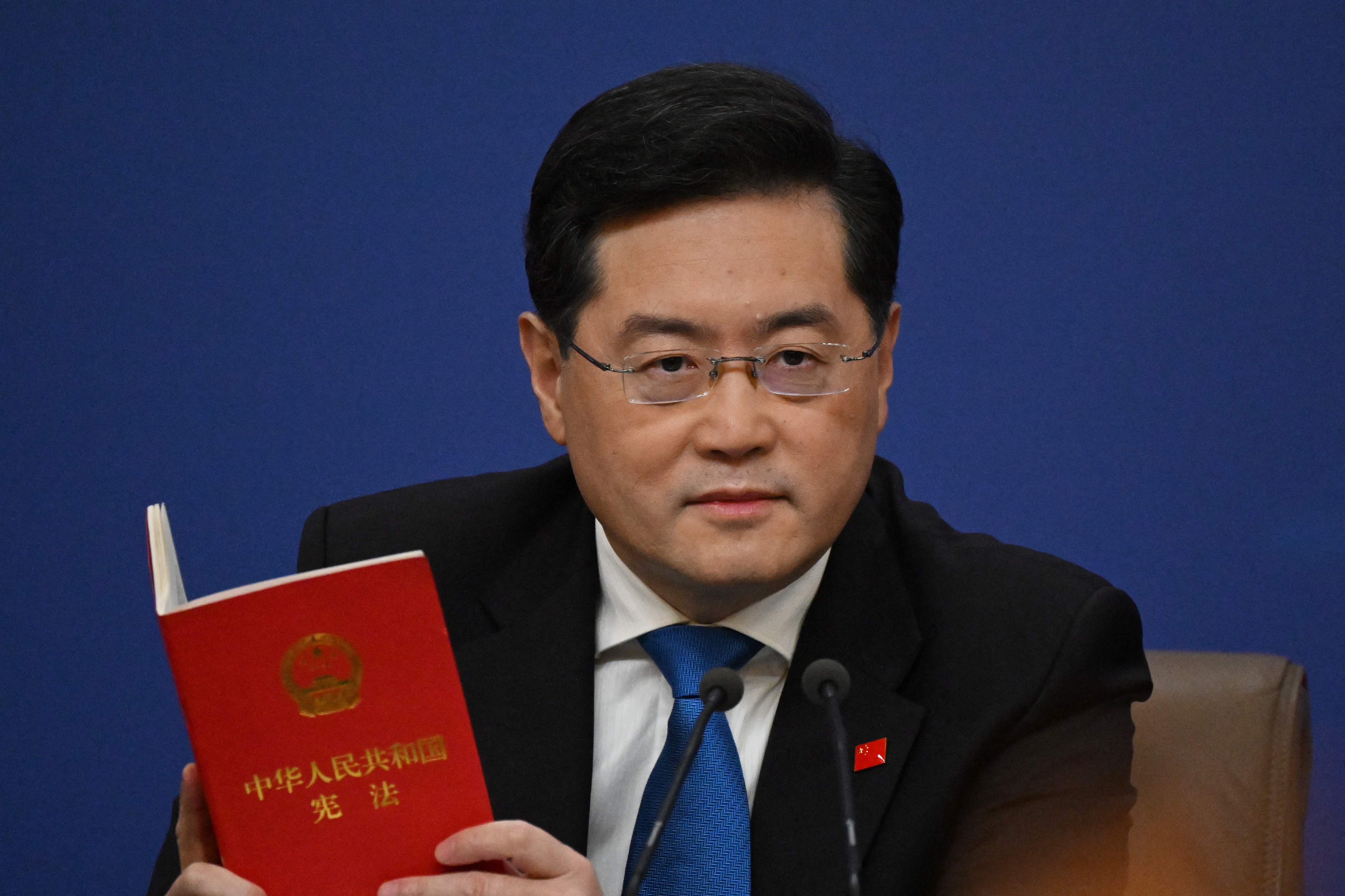 Chinese foreign minister Qin Gang holds a copy of China’s constitution during a press conferencein March 2023