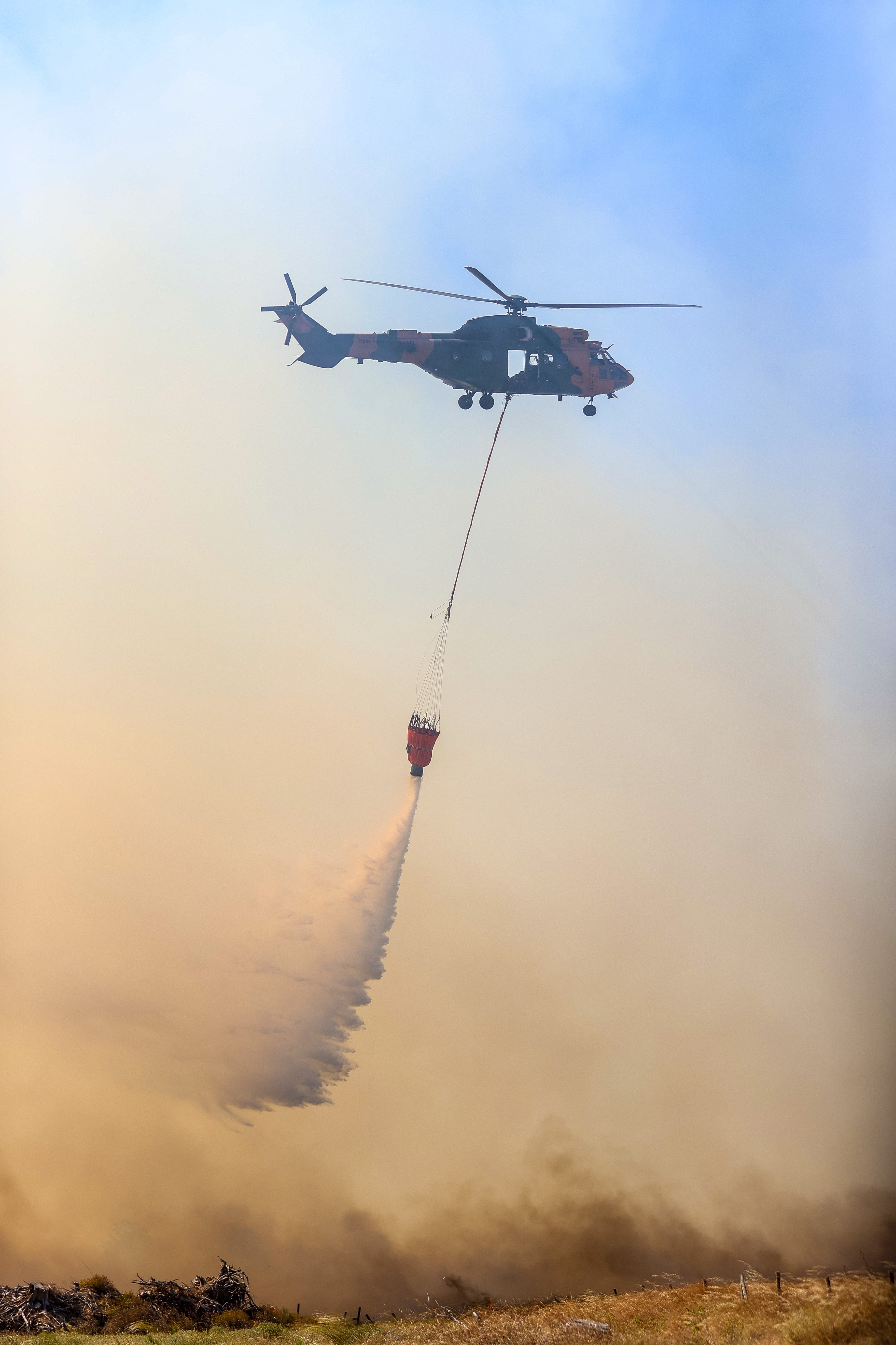 A firefighter helicopter drops water on wildfire as firefighter teams conduct extinguishing works by land and air to control wildfires in Canakkale, Turkiye on July 17, 2023