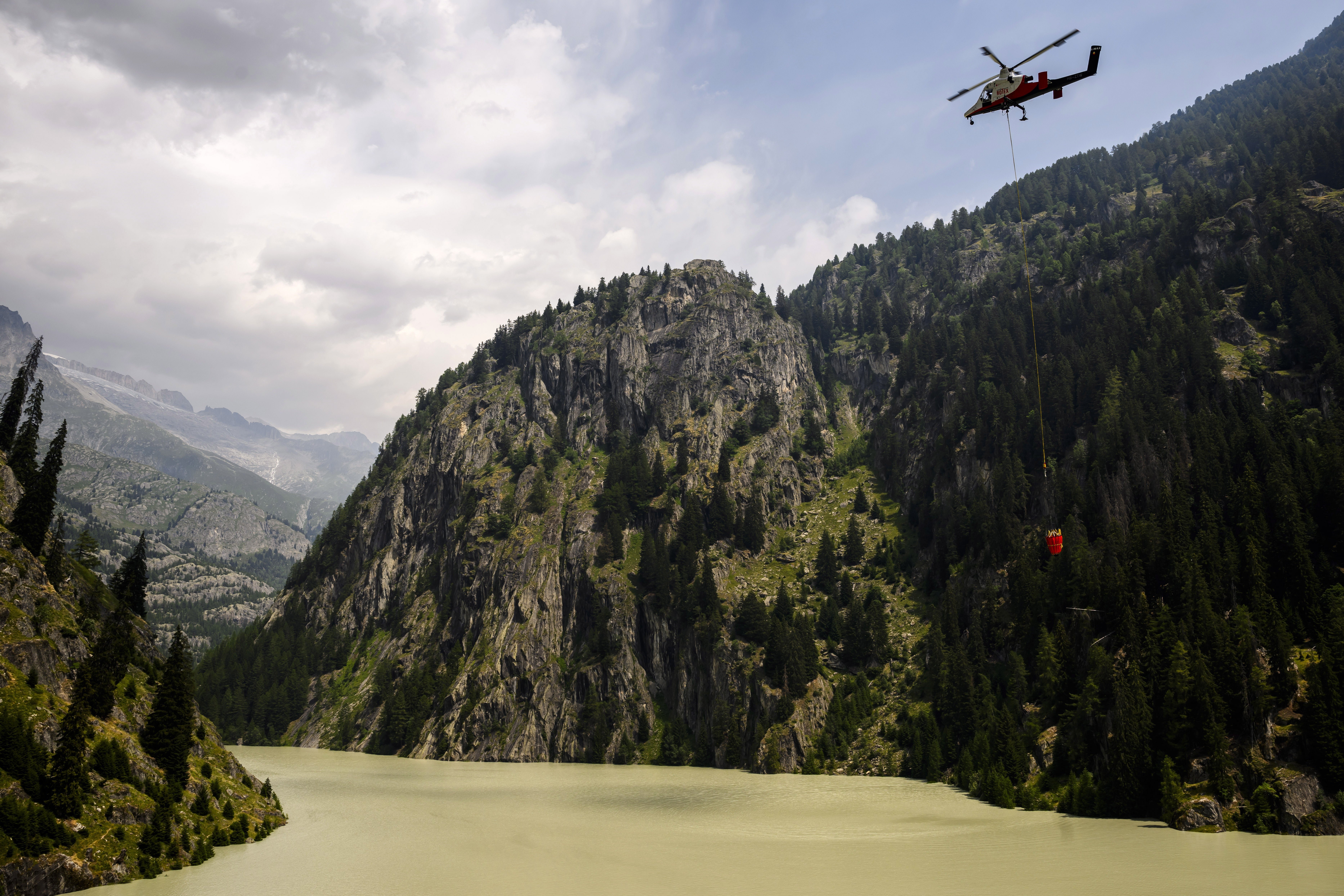 A helicopter refills its bucket over the Gibidum dam to extinguish the forest fire above the Switzerland communes of Bitsch and Ried-Moerel