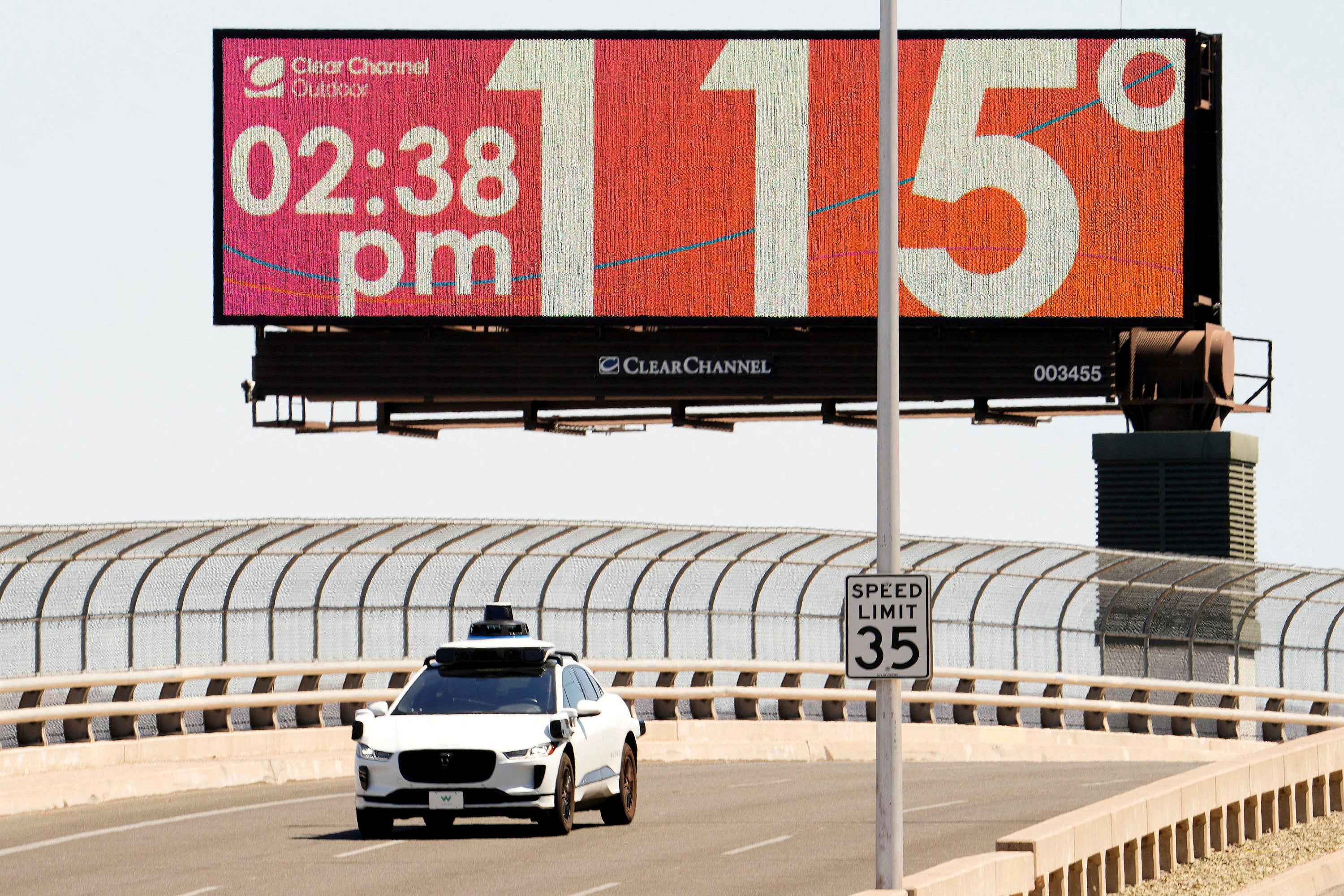 A Waymo self-driving car on Seventh Street as the temperature of 115 degrees is displayed on a digital billboard in downtown Phoenix, Arizona on Monday