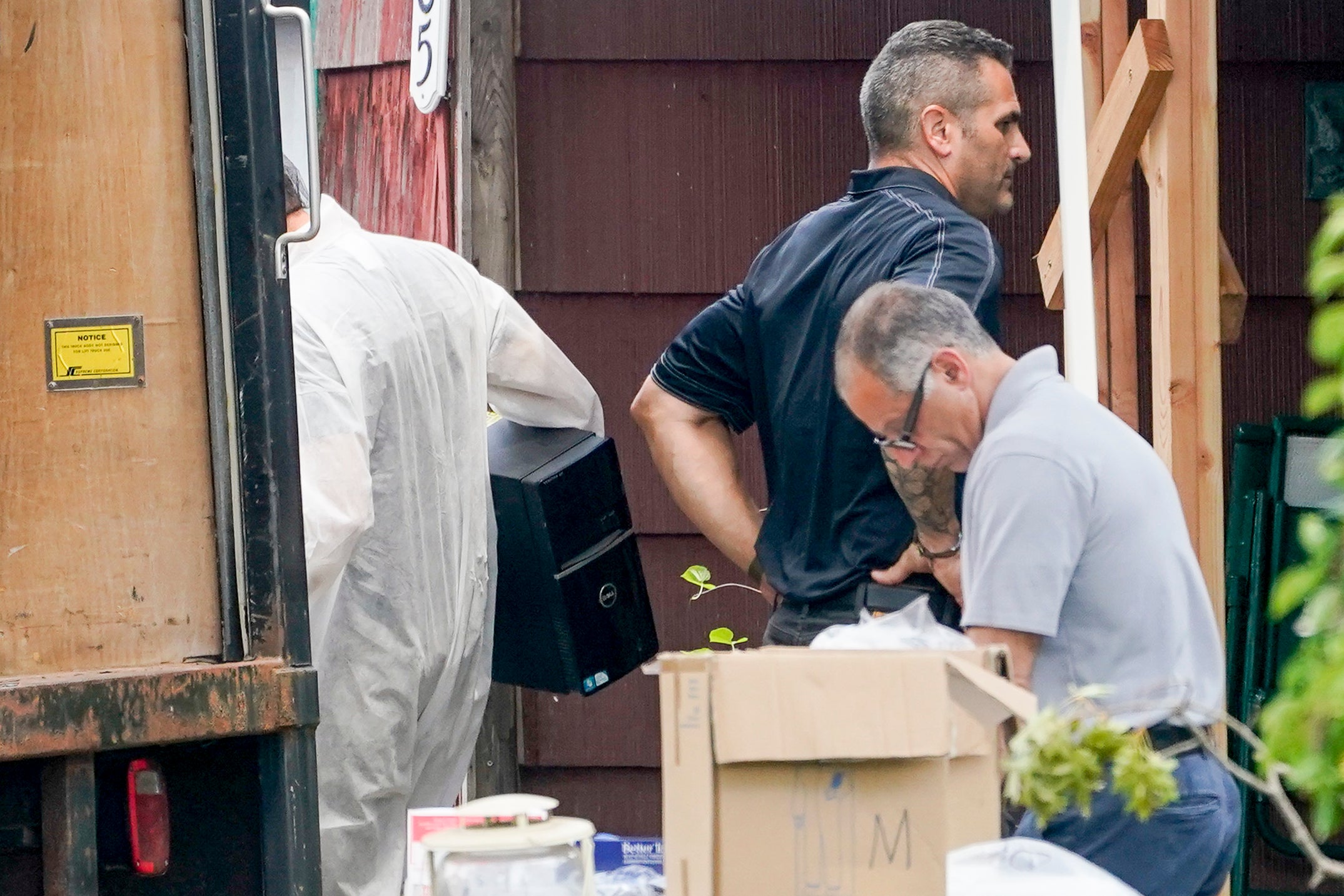 Authorities remove a computer tower as they search the home of suspect Rex Heuermann