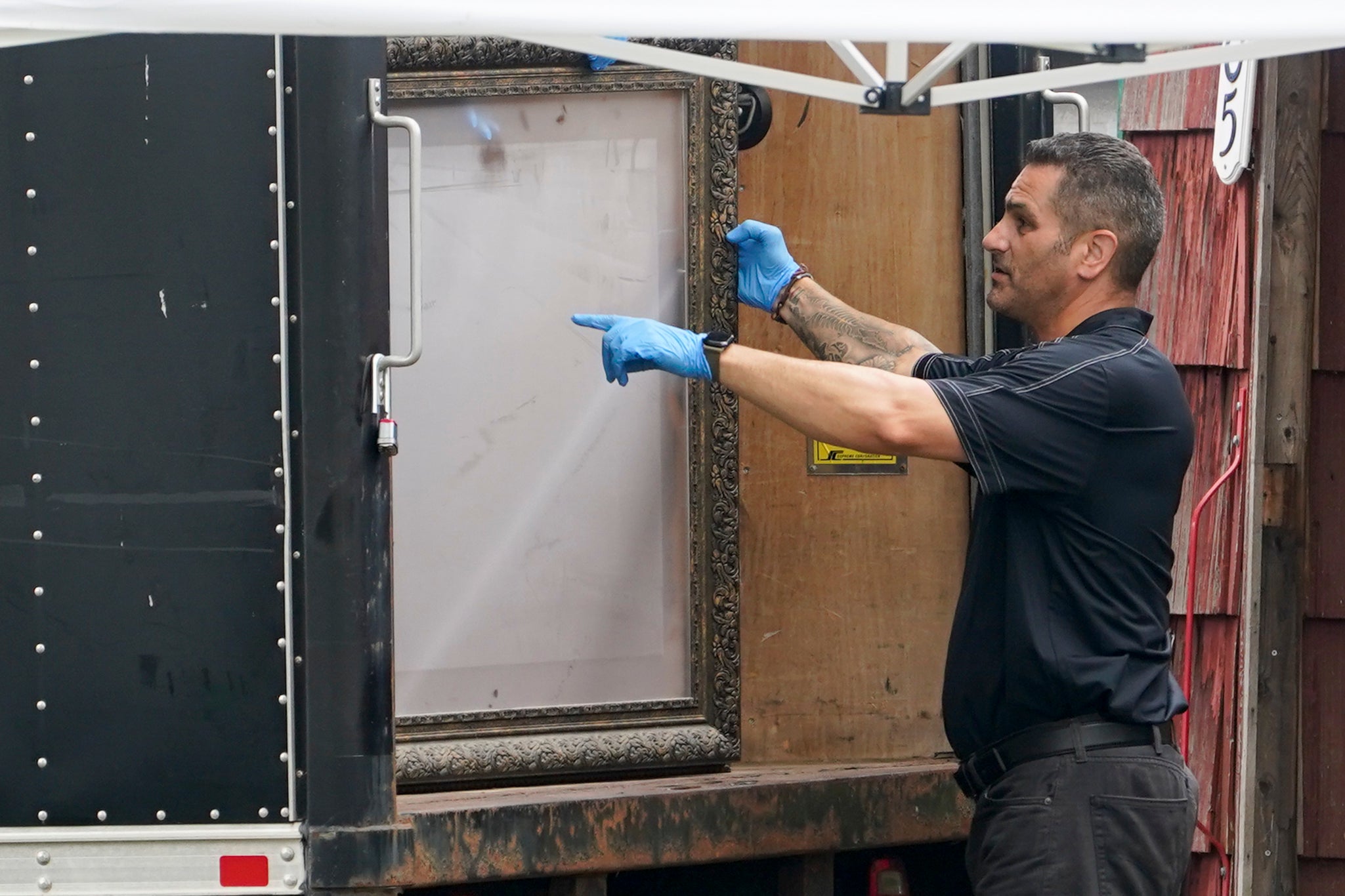 Authorities remove a picture frame as they search the home of suspect Rex Heuermann