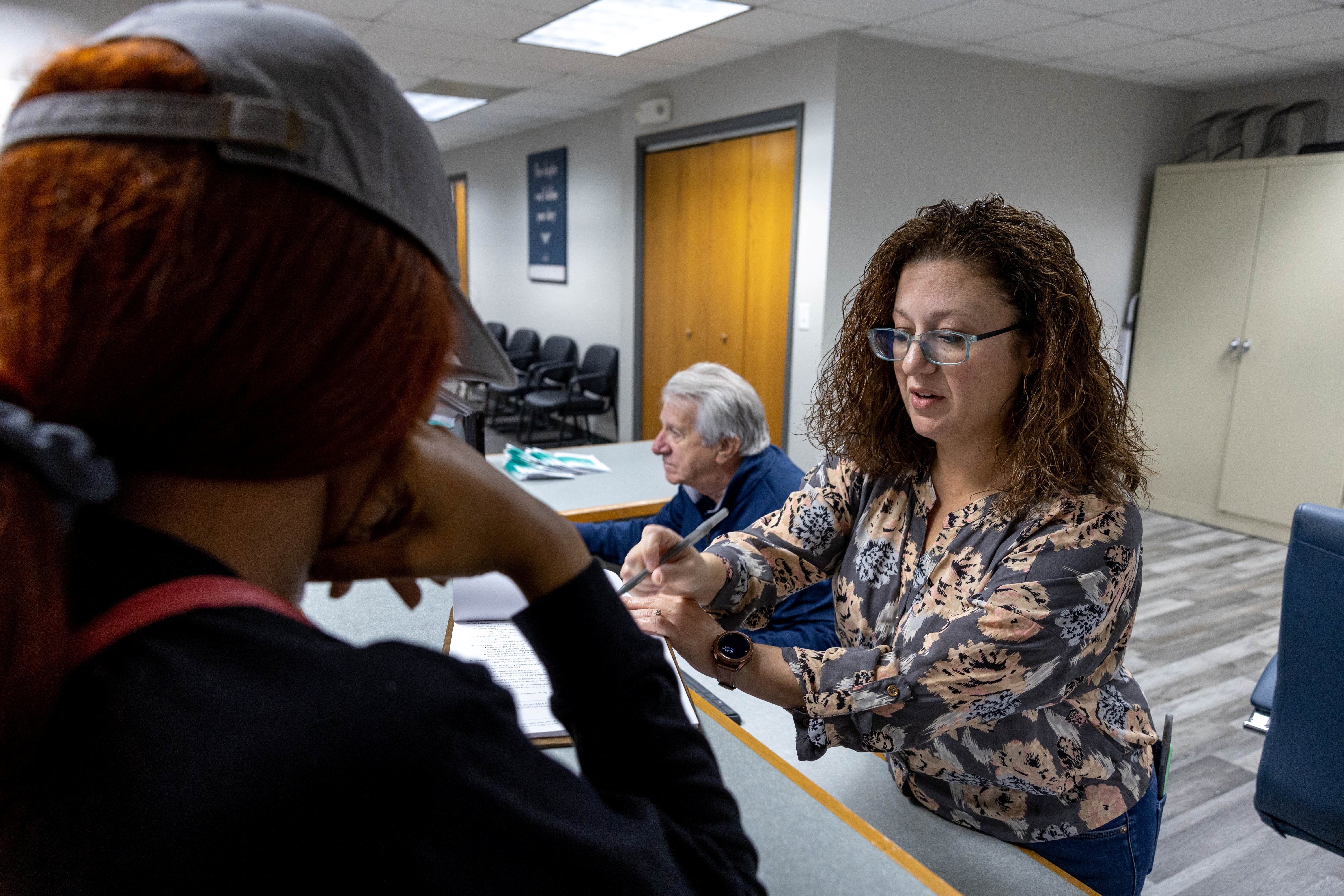 Gallegos speaks with a patient at Alamo Women's Clinic as her father sits behind her, in Carbondale, Illinois