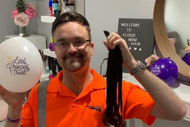 Stuart Hughes, who works for Network Rail in Birmingham, with the 10 18-inch ponytails he grew to make wigs for young cancer patients (Network Rail/PA)