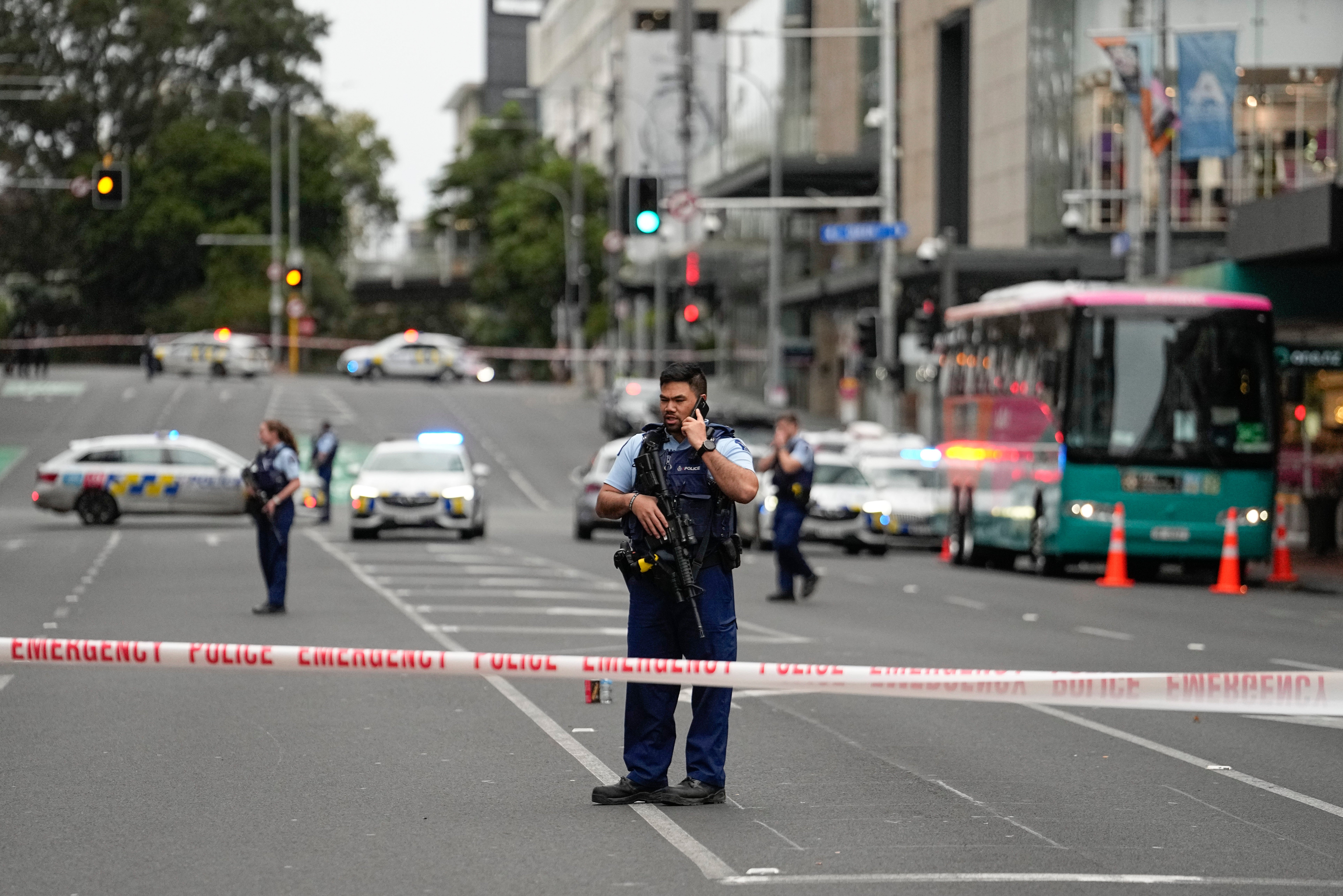 Armed New Zealand police officers stand at a road block in the central business district following a shooting in Auckland
