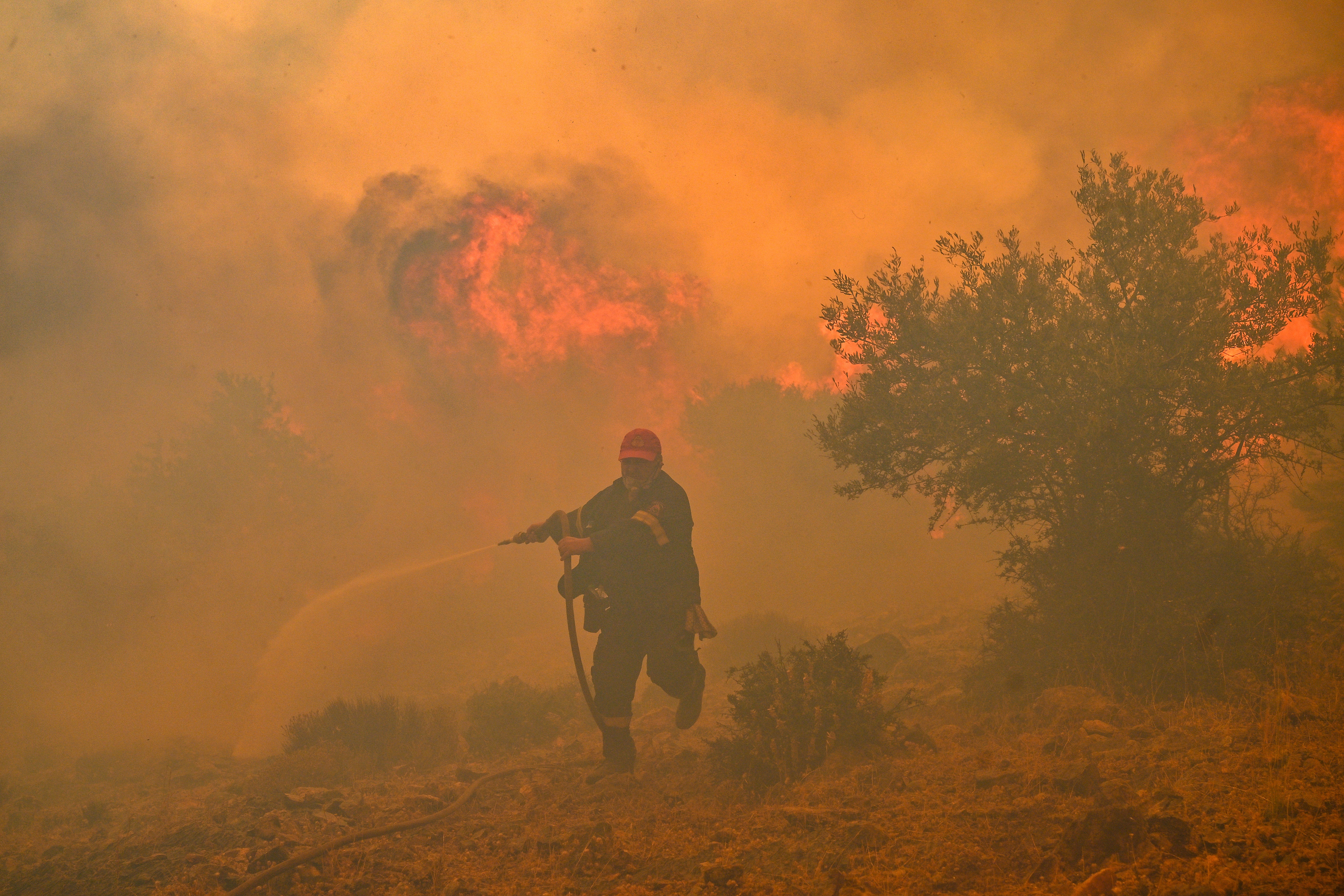 A fireman runs away from blazes as he tries to control a wildfire in New Peramos, near Athens