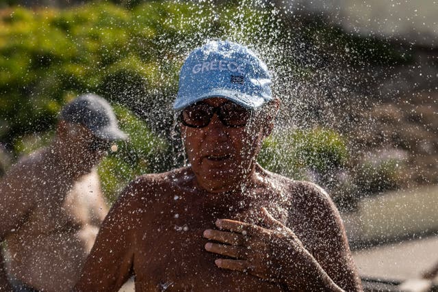 <p>A bather takes a shower during a hot day at Alimos beach near Athens amid scorching heatwaves </p>