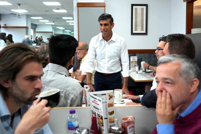 Prime Minister Rishi Sunak talking to people at the Rumbling Tum cafe in Uxbridge (Carl Court/PA)