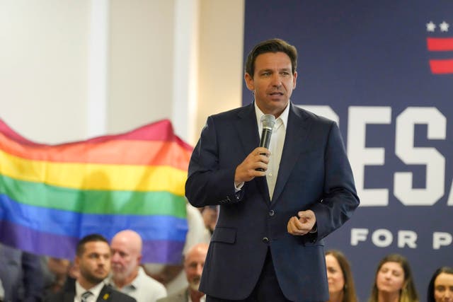 <p>Florida Gov. Ron DeSantis speaks during a campaign event on Monday as protesters raise a gay rights flag; the Republican presidential hopeful days later downplayed the 6 January insurrection, calling it ‘a protest’ that devolved </p>
