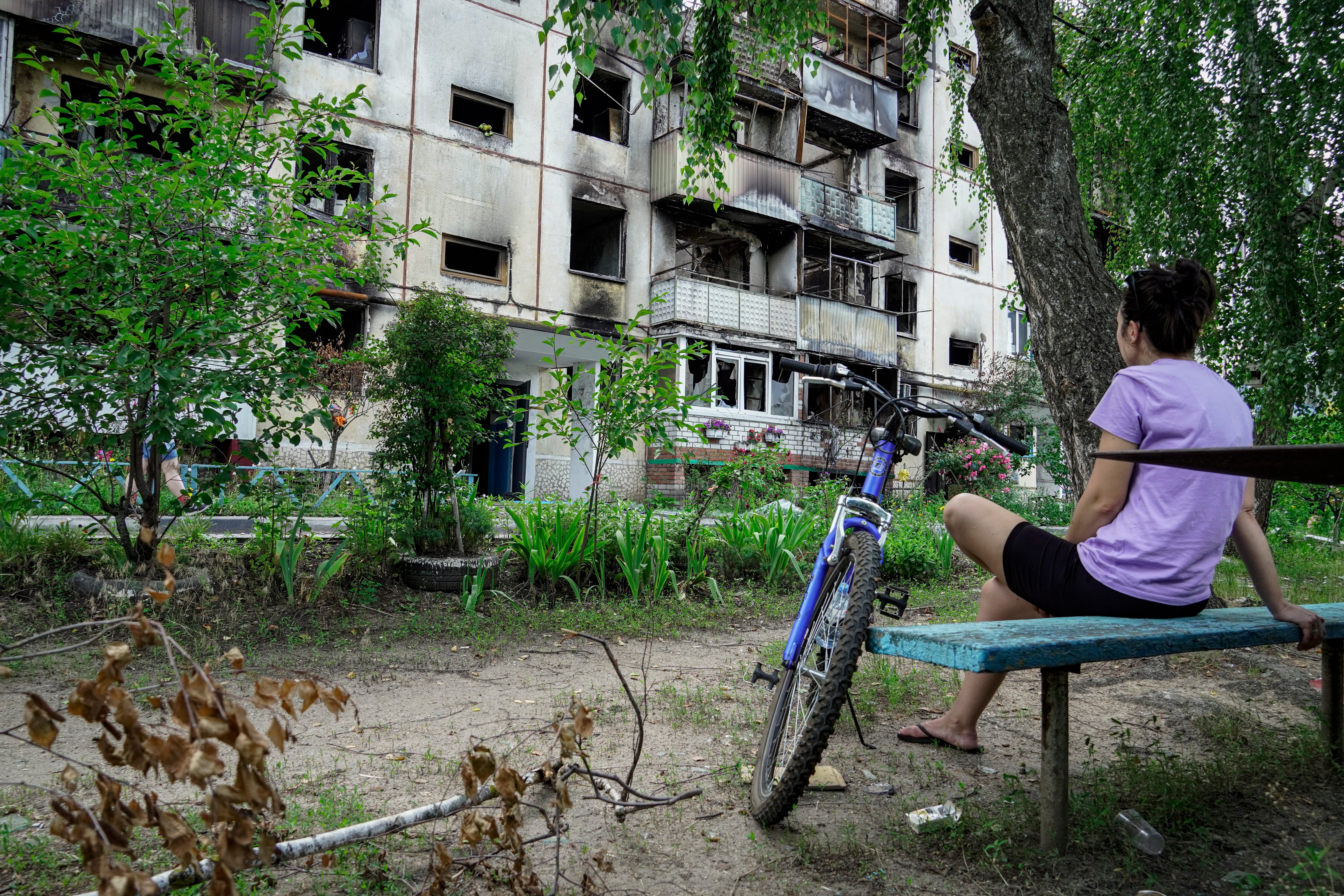 A local woman sits in front of the damaged residential building in Shebekino, Belgorod region, Russia