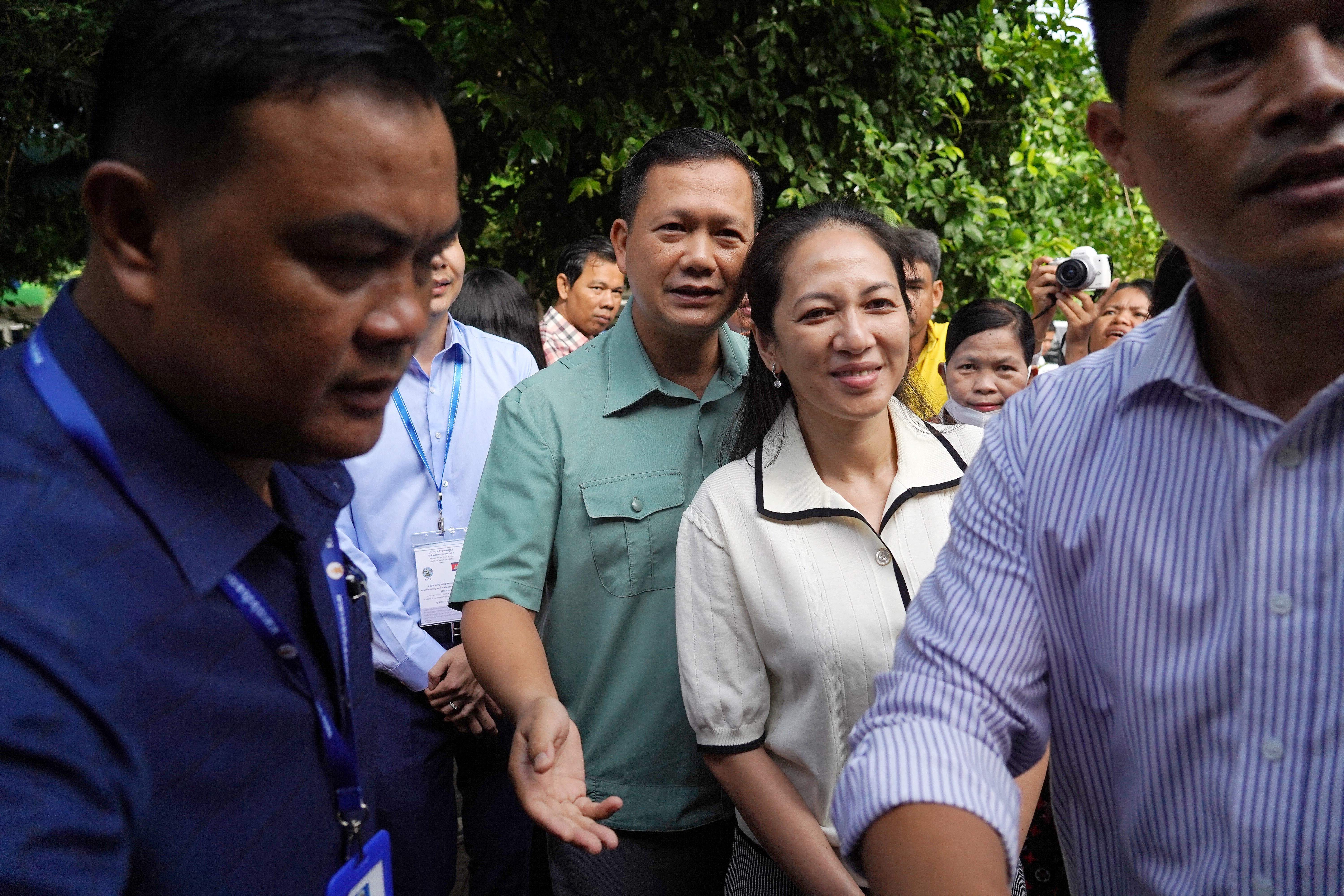 Hun Manet (Center-L), commander of the Royal Cambodian Army and eldest son of Prime Minister Hun Sen, with his wife Pich Chanmony (C) arrive at a polling station in Phnom Penh on 23 July, 2023