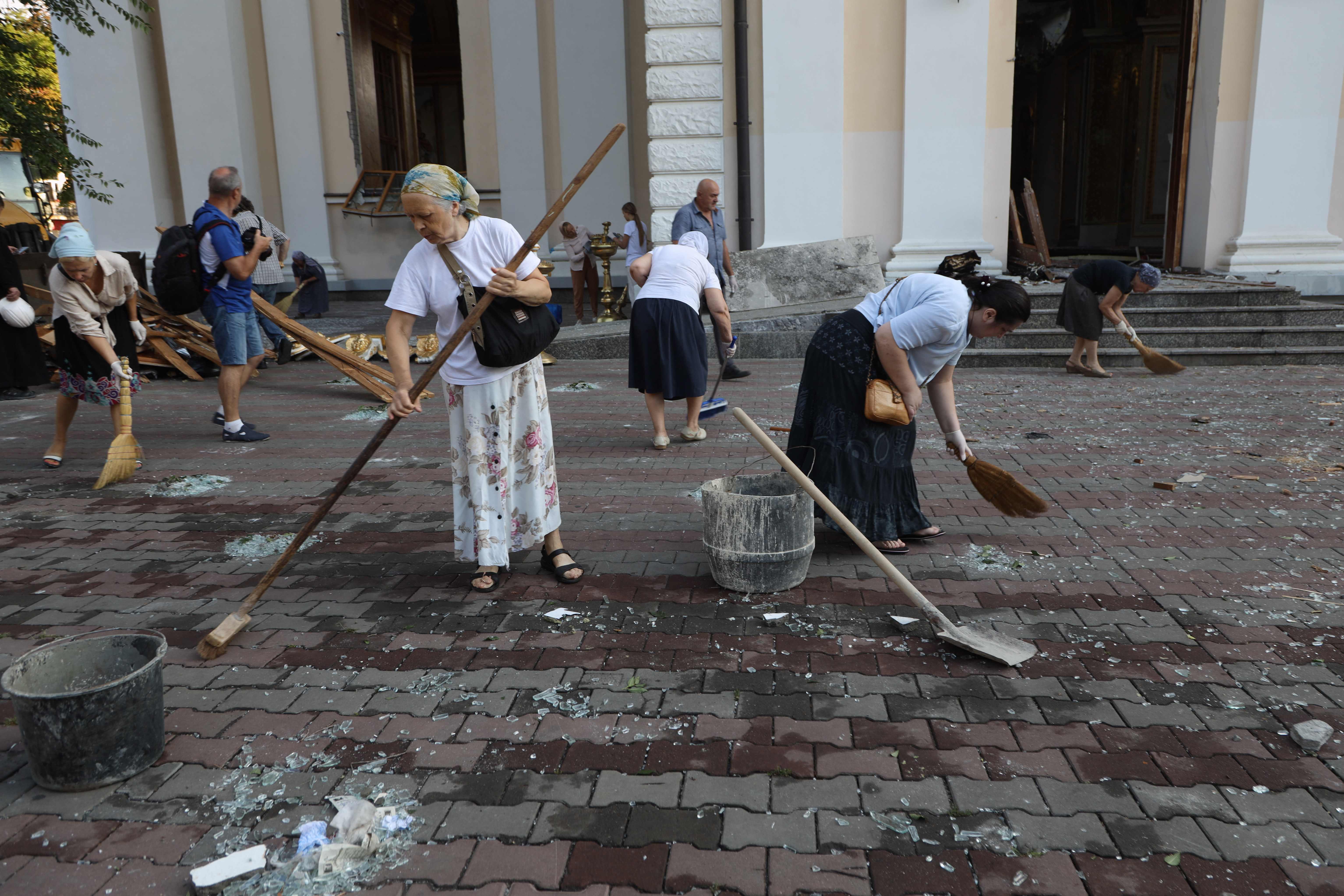 Local residents clean an area outside the damaged Transfiguration Cathedral in Odesa