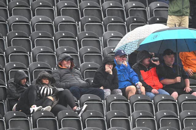 <p>Frustrated spectators look on from the party stand as rain delays the start of play on the fifth day of the Ashes at Old Trafford </p>