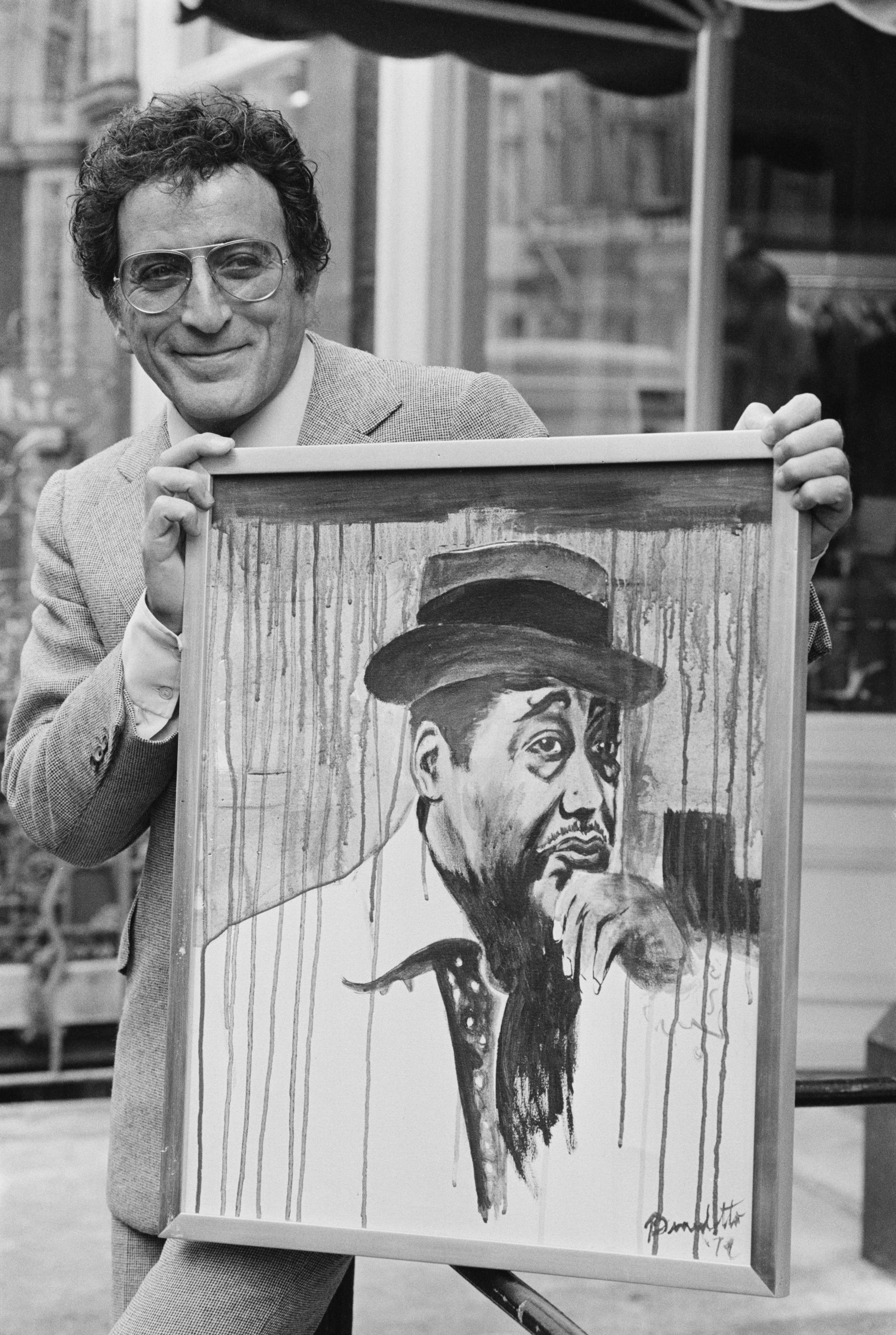 Holding one of his paintings, which he created under the name Anthony Benedetto, in 1977