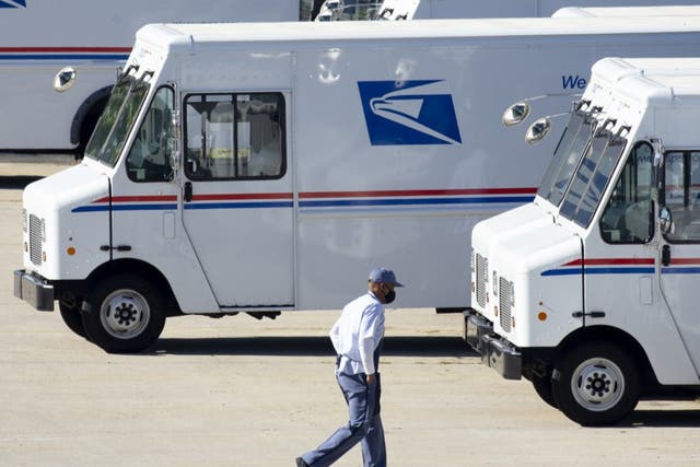 <p>A mail carrier walks to a truck at a United States Postal Service (USPS) processing and distribution center in Washington, DC, on 8 October 2020</p>
