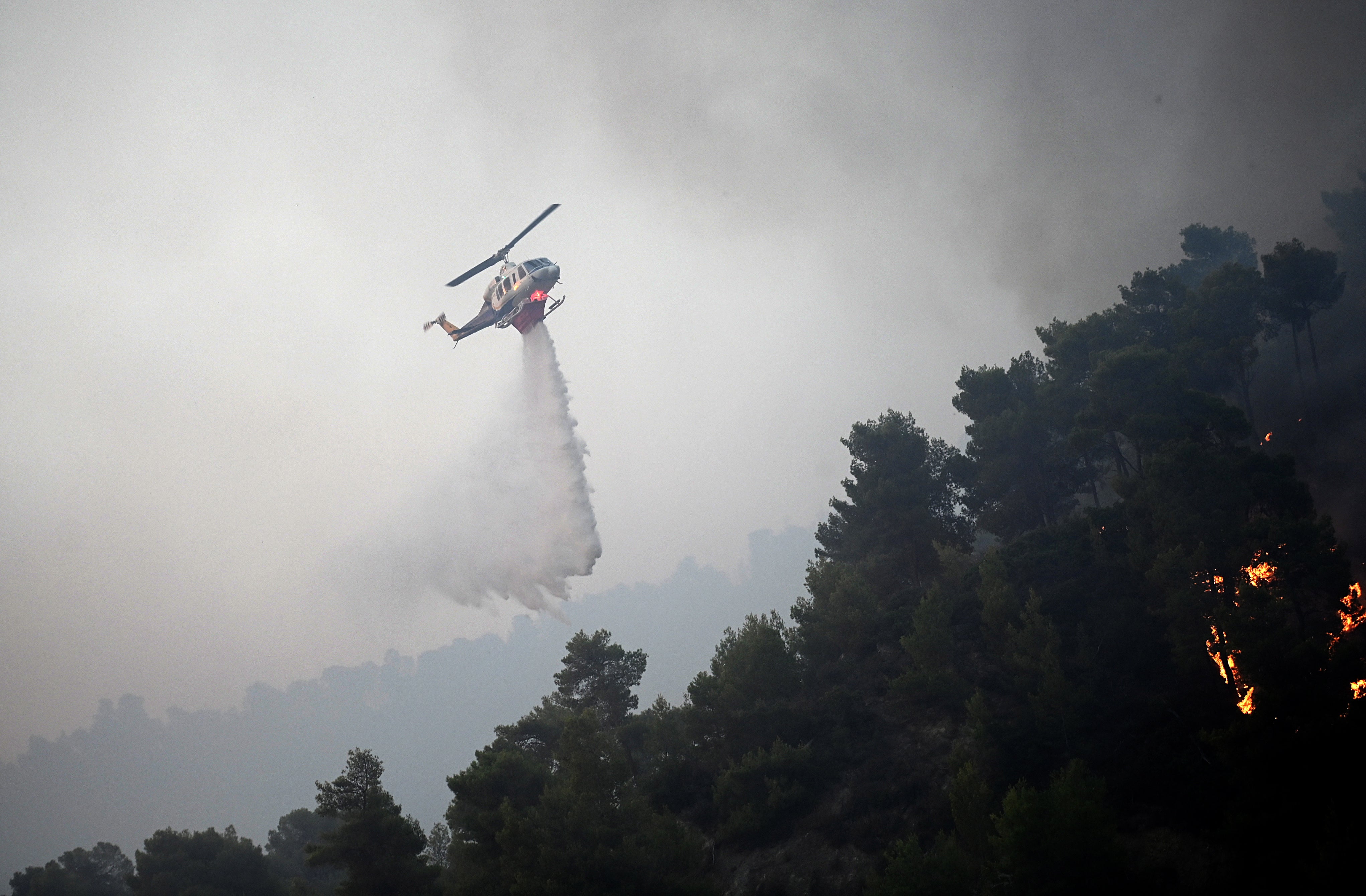 A firefighting helicopter drops water to extinguish a wildfire, in Diakopto, Egio, Greece